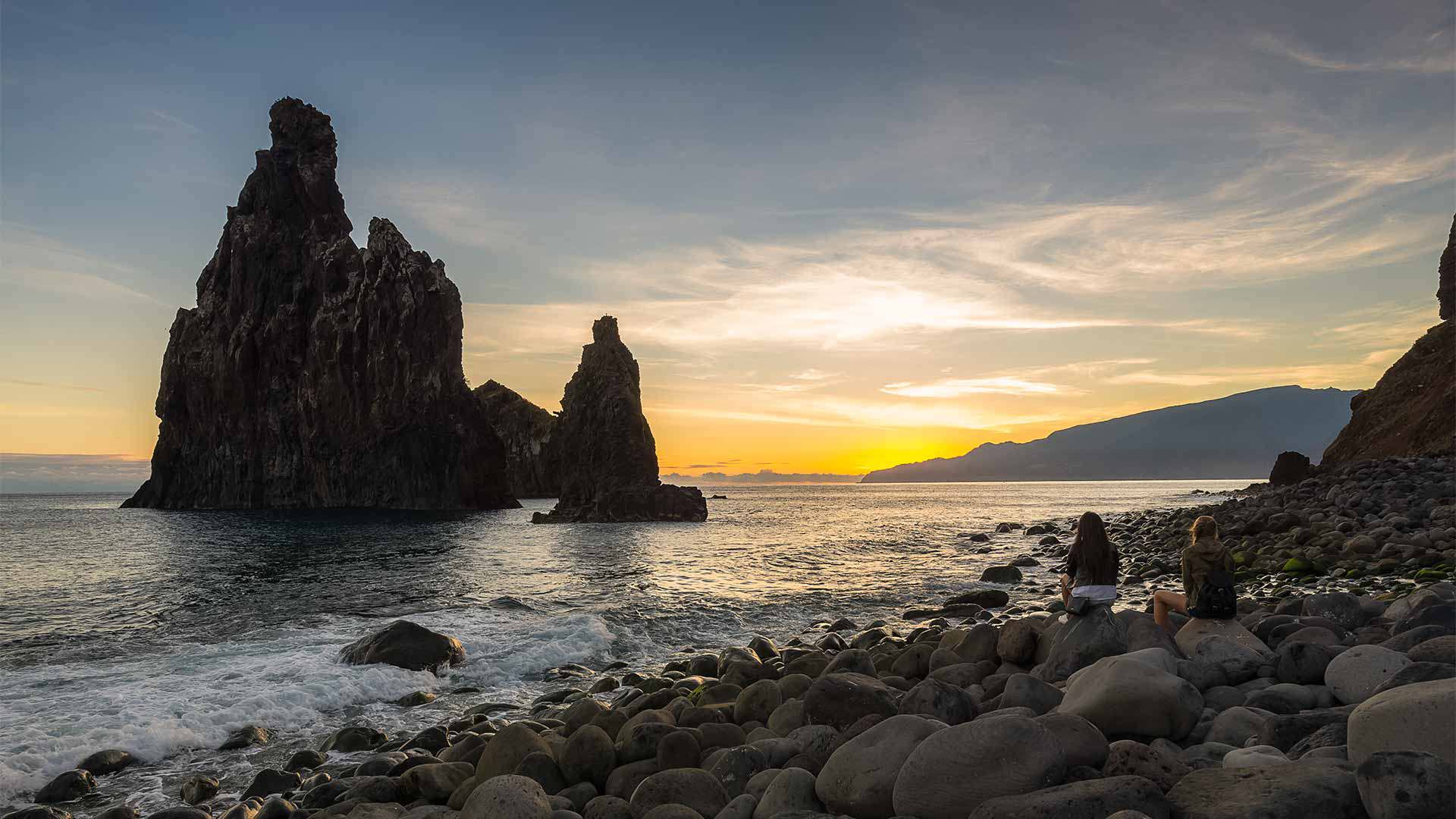 Formation rocheuse en mer au coucher du soleil, entourée de pierres à Madère.