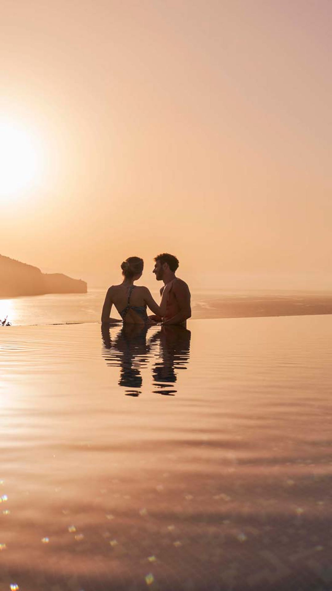 Couple in a pool watching the sunset.