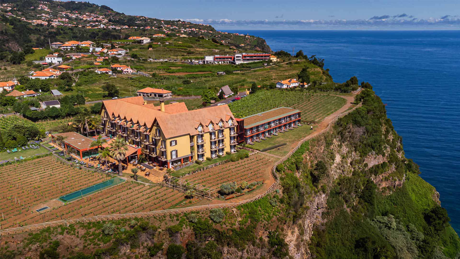 Hôtel jaune entouré de vignobles avec vue sur la mer à Madère.