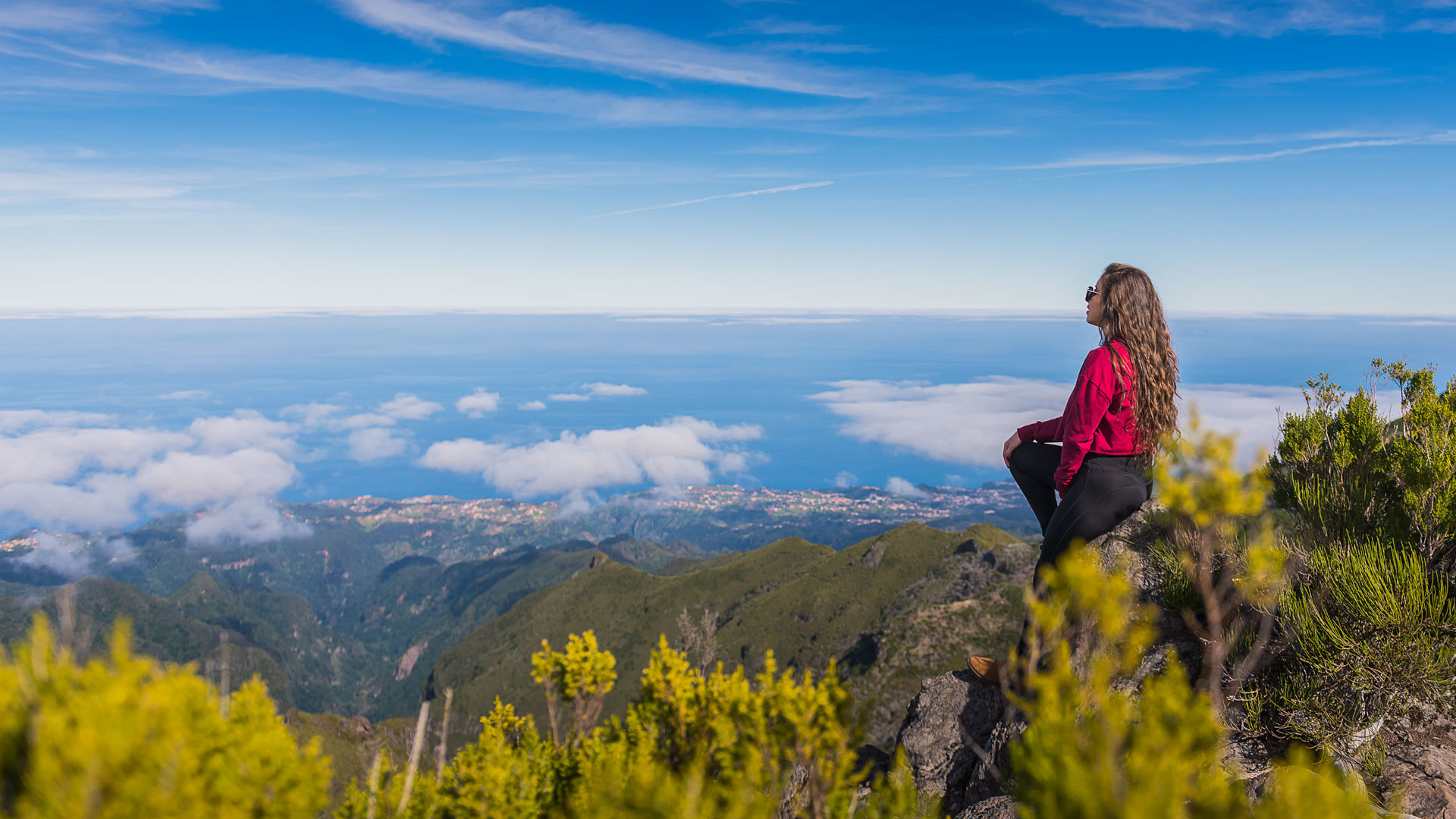 Woman sitting on rock overlooking mountains and sea in Madeira.