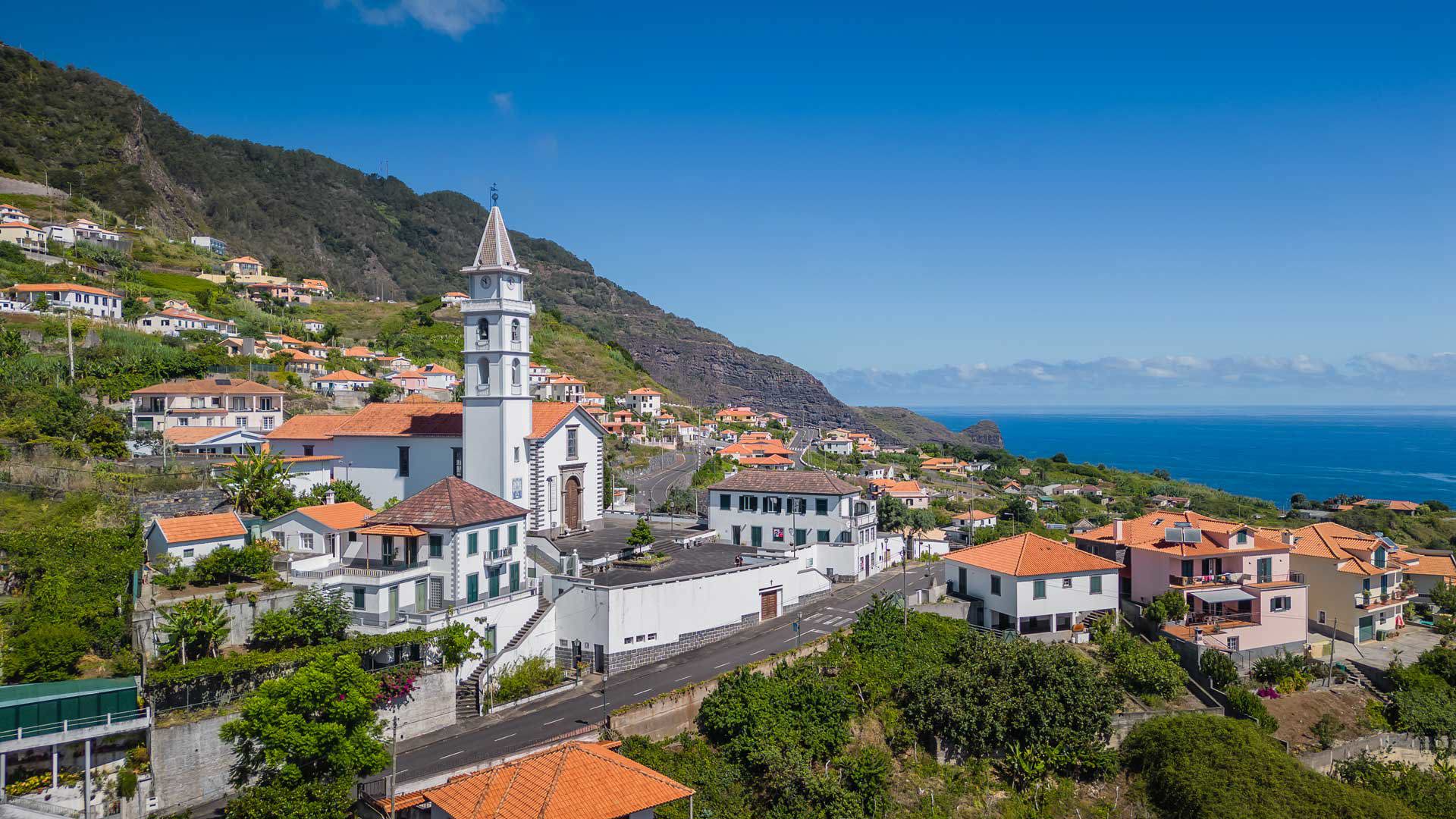 Église et maisons entourées de nature dans le paysage de Madère.