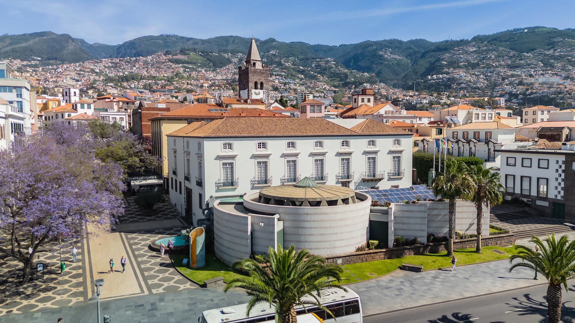Stadt mit Gebäuden, Bäumen, Straße und fahrenden Bus.