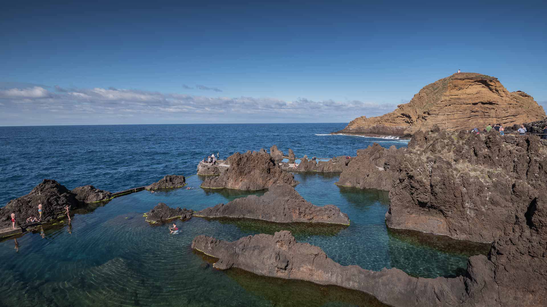 Naturpool am Meer zwischen Felsen, mit einem großen Felsen im Vordergrund.