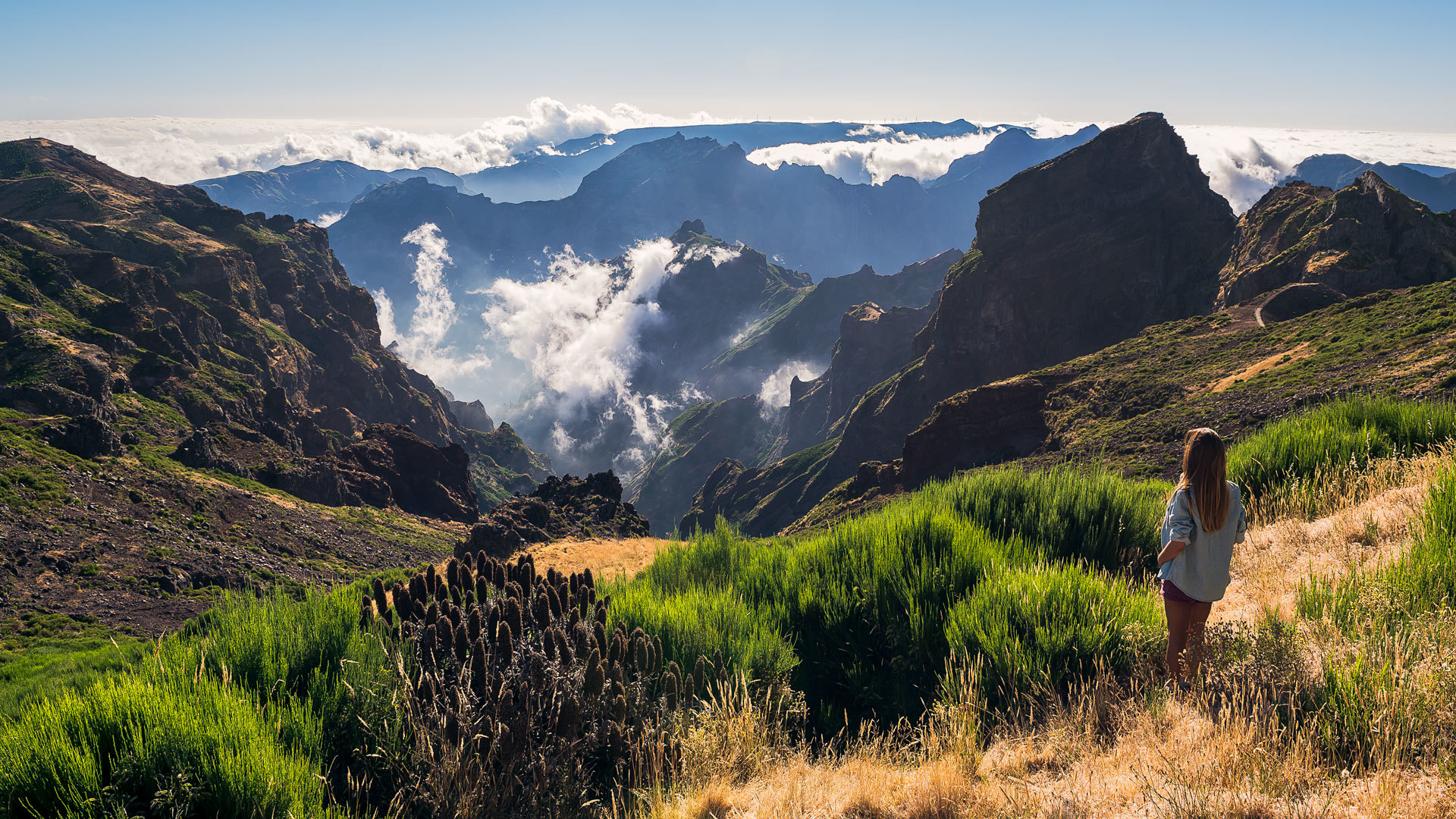 Hombre en medio de la naturaleza, con montaña y nubes al fondo en Madeira.