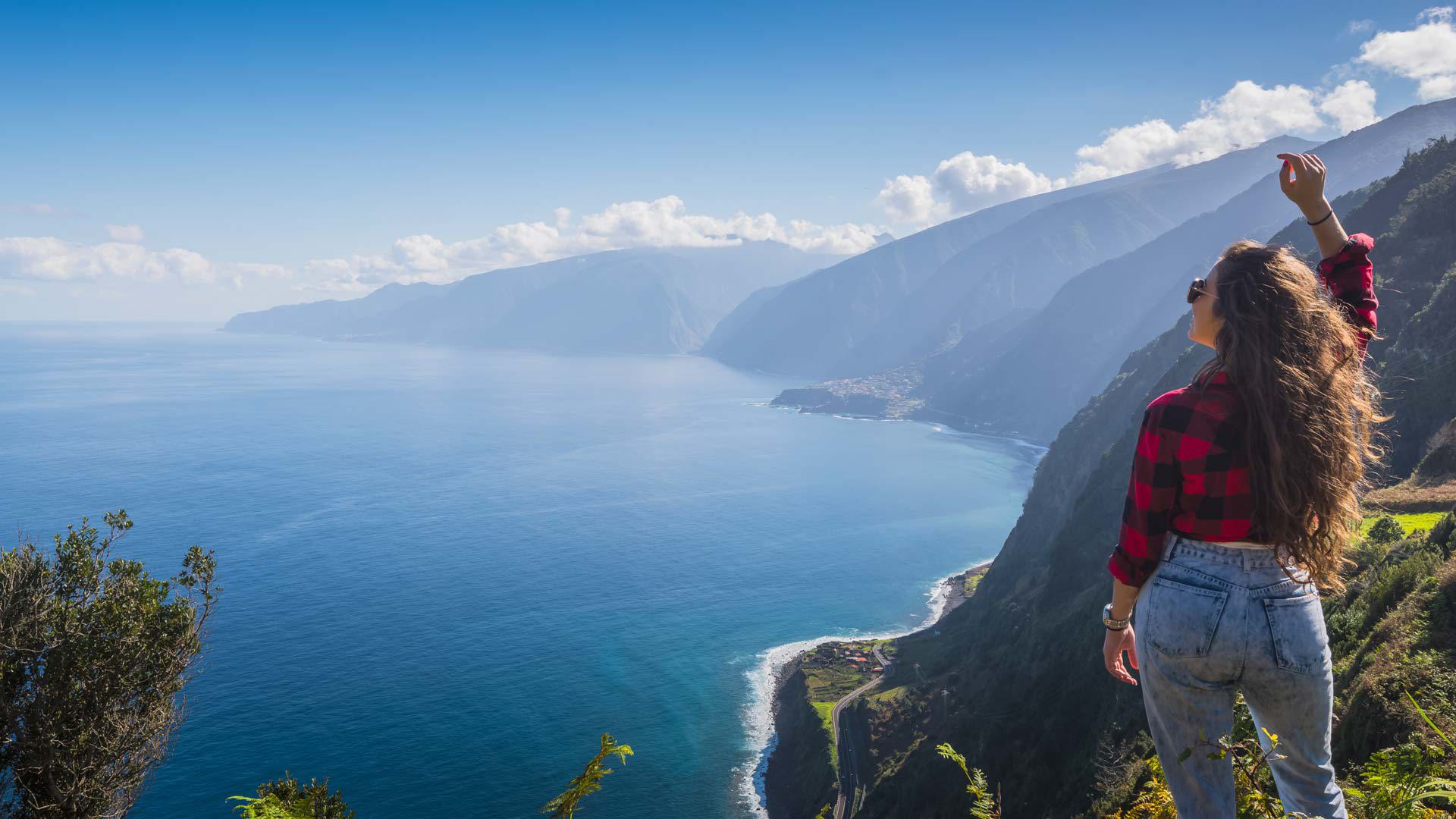 Woman at viewpoint observing the coast and sea in Madeira.