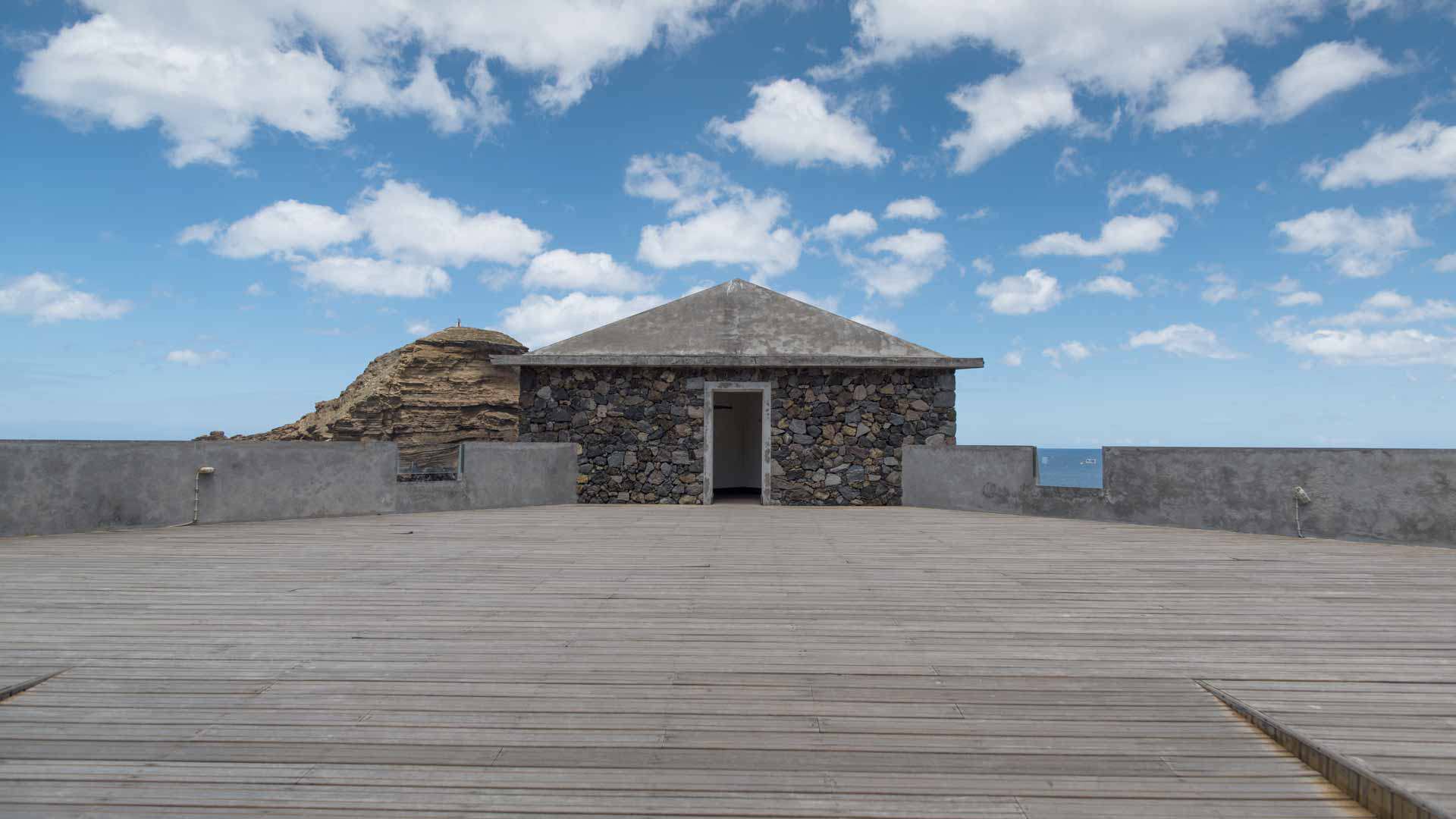 Stone house with clouds in the sky behind.