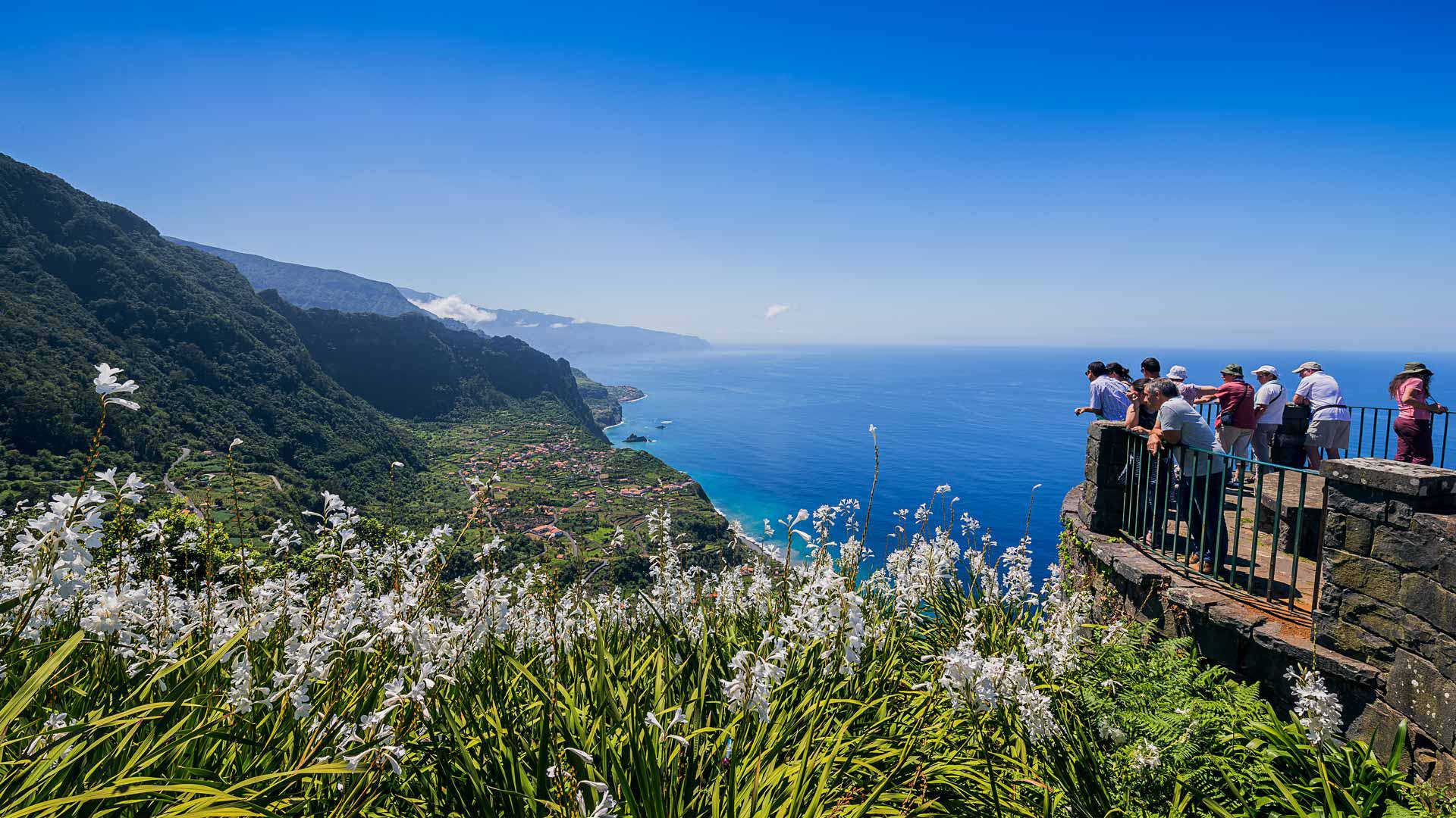 Personnes à un belvédère avec vue sur la mer et les montagnes.
