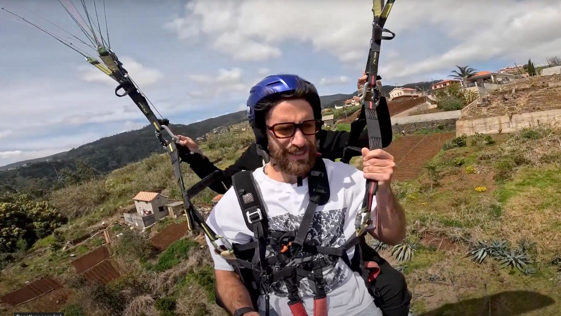 Mann beim Gleitschirmfliegen am Himmel, mit Helm.