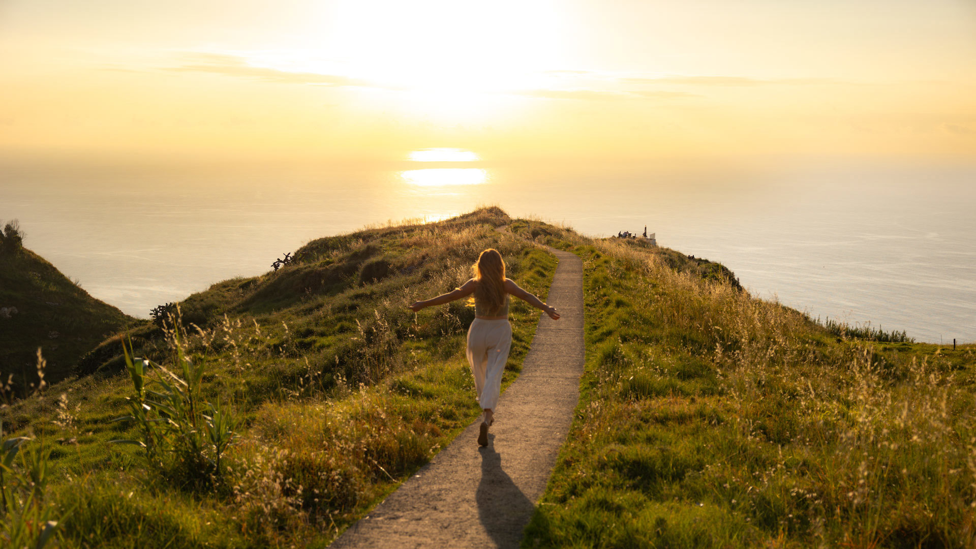 Frau läuft am Aussichtspunkt Boa Morte bei Sonnenuntergang, mit Vegetation und Meer im Hintergrund.