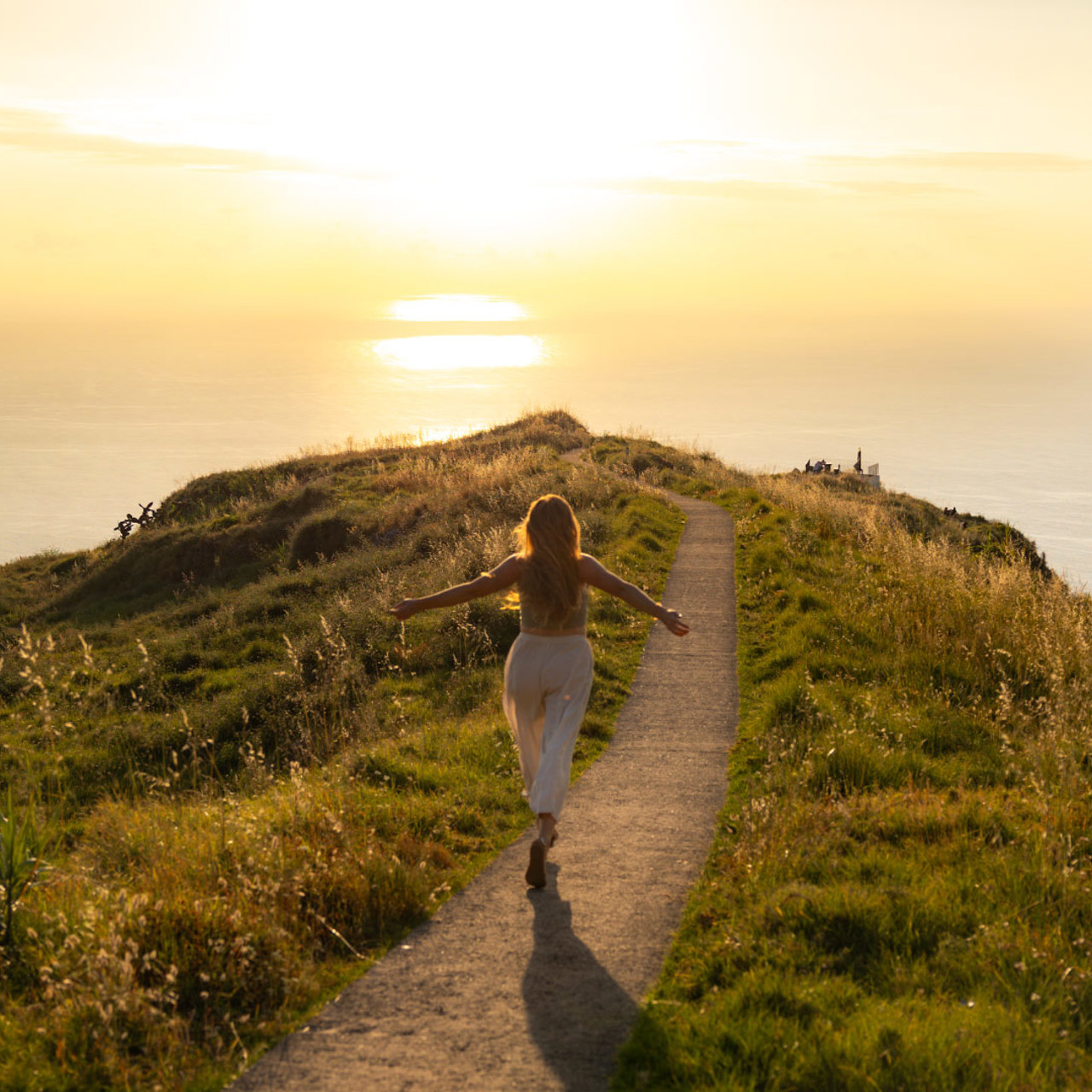 Frau läuft am Aussichtspunkt Boa Morte bei Sonnenuntergang, mit Vegetation und Meer im Hintergrund.