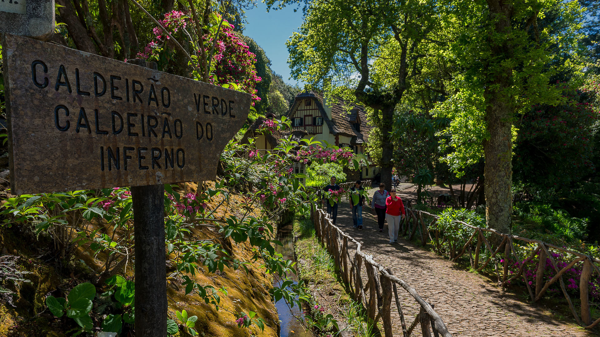 Person wearing red jacket near wooden fence and information sign in nature.