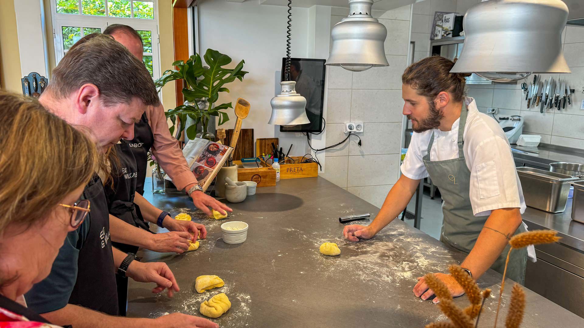 Taller de gastronomía con chef y personas preparando comida típica de Madeira.