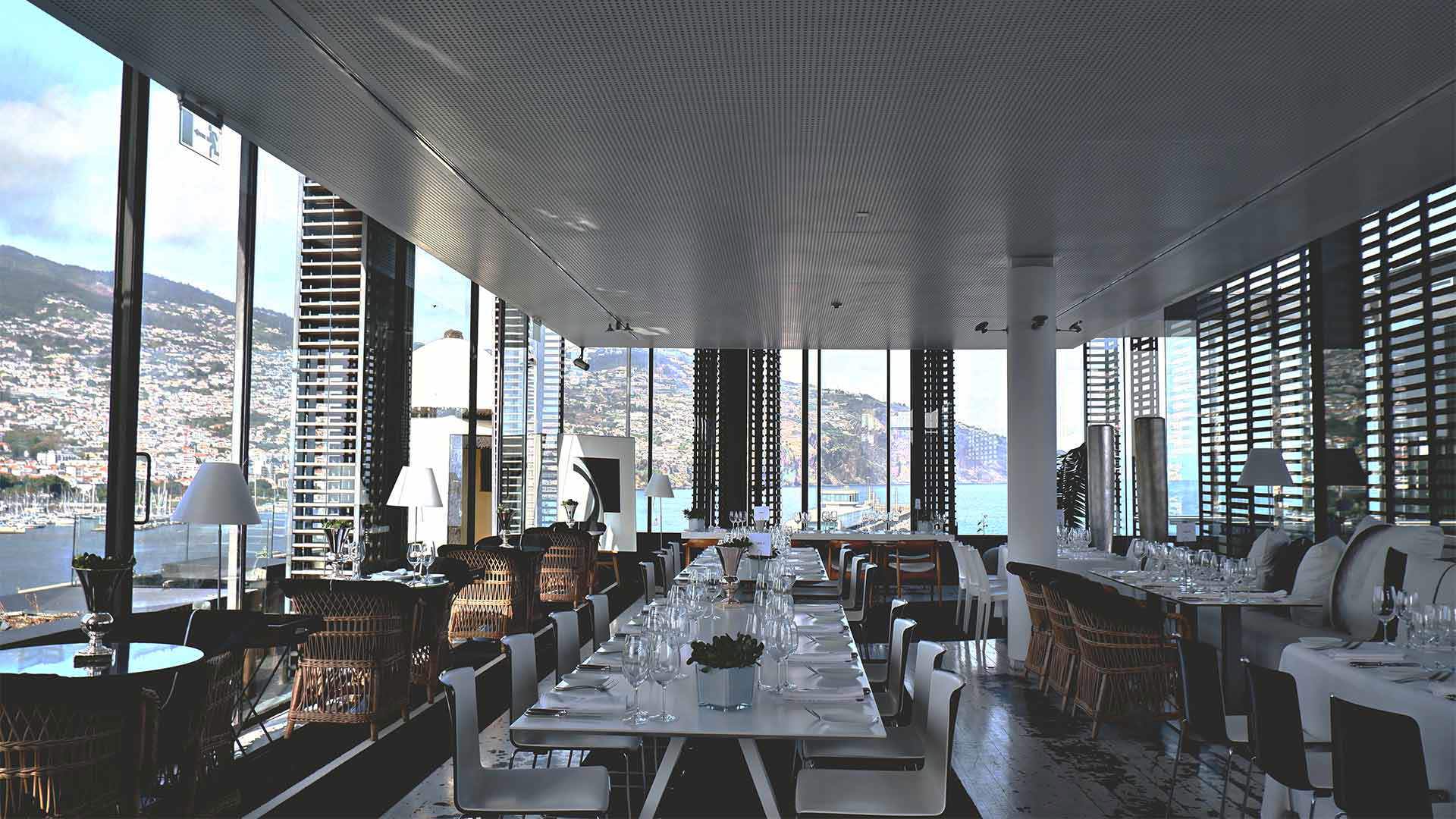 Tables set with glasses, plates, and cutlery, overlooking the bay.