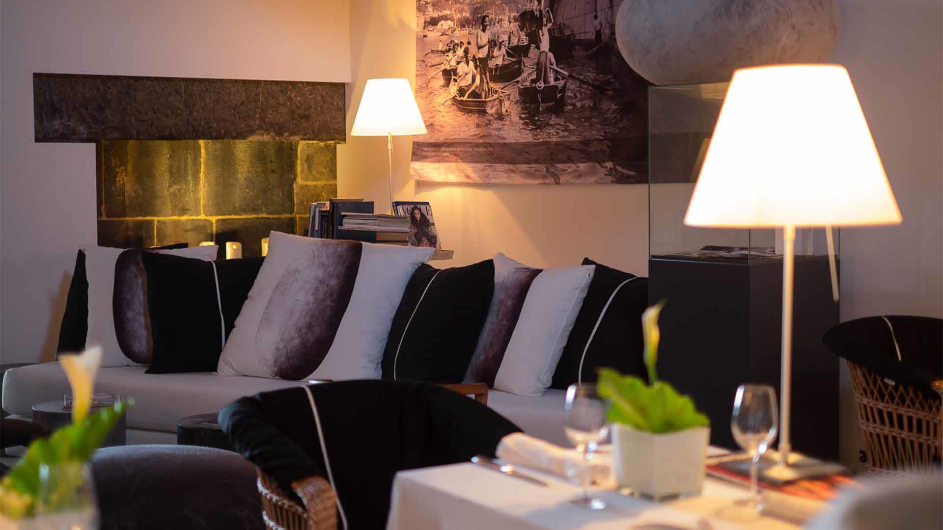 Sofa with multiple cushions and lit lamp.