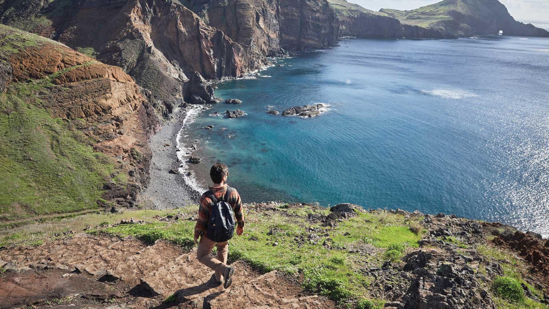 Man walking along a trail by the pebble beach with sea view.