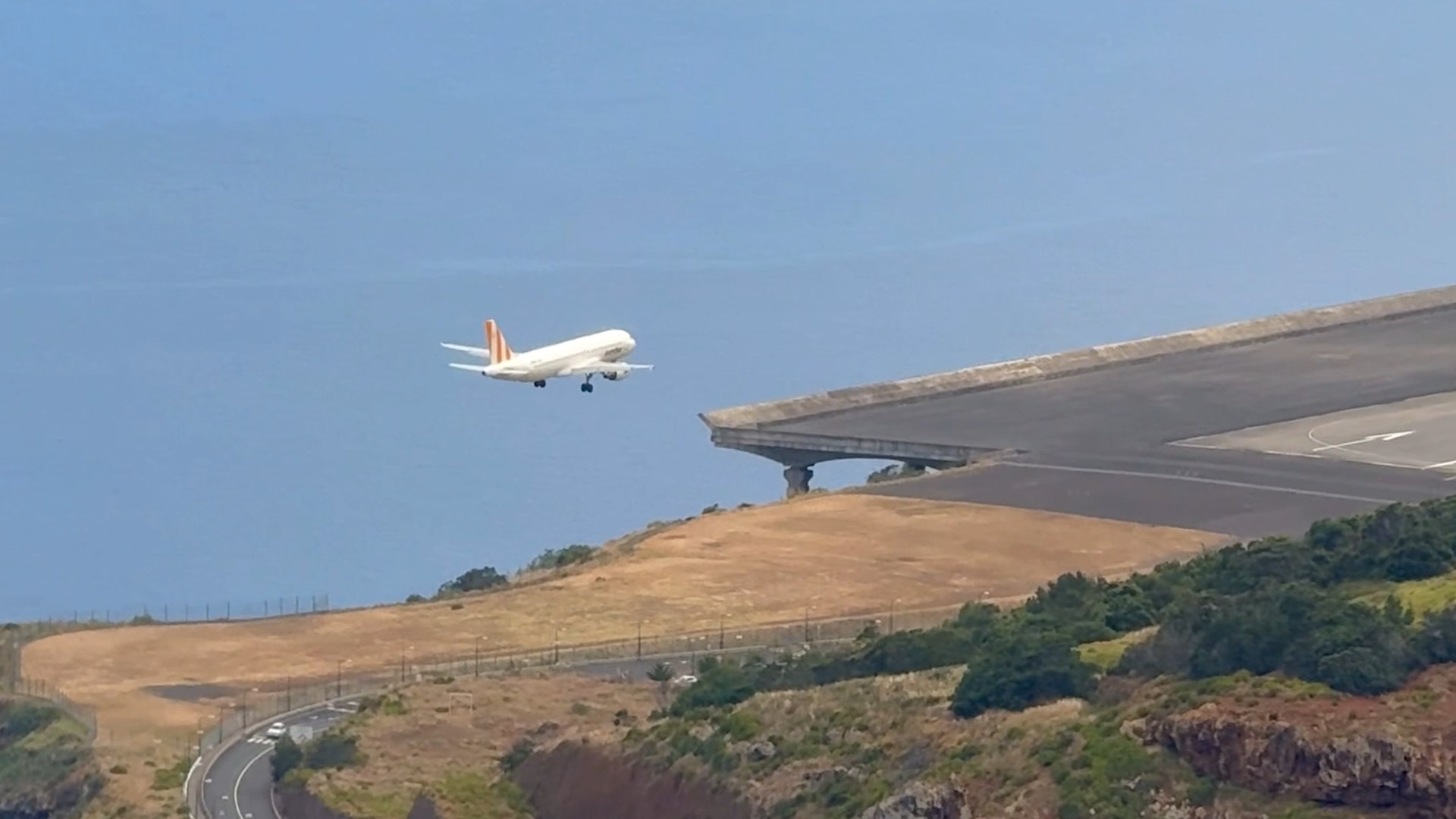 Flugzeug landet am Flughafen Madeira, mit Meer im Hintergrund.
