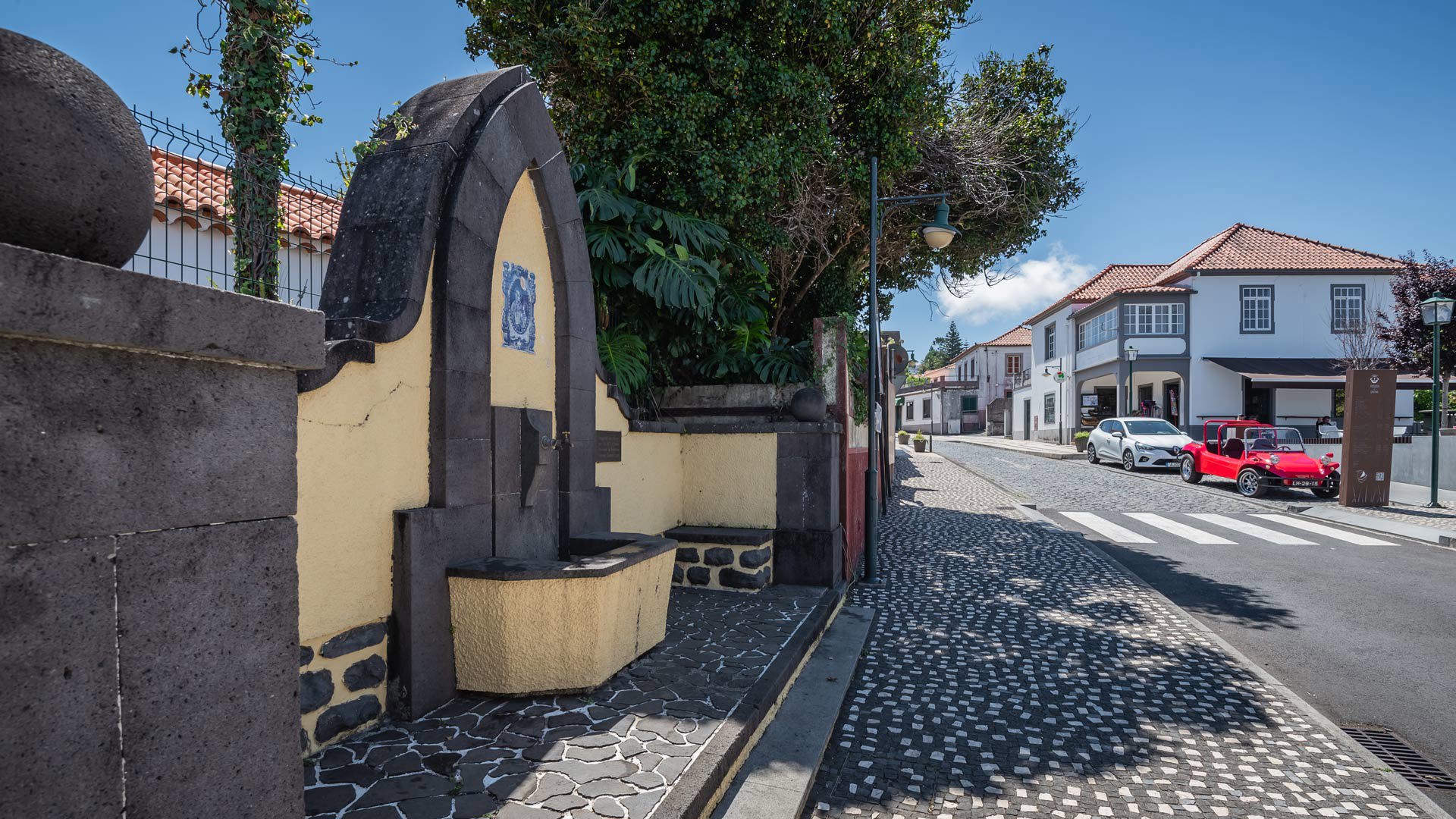 Brunnen neben Baum und gepflastertem Gehweg an der Straße auf Madeira.