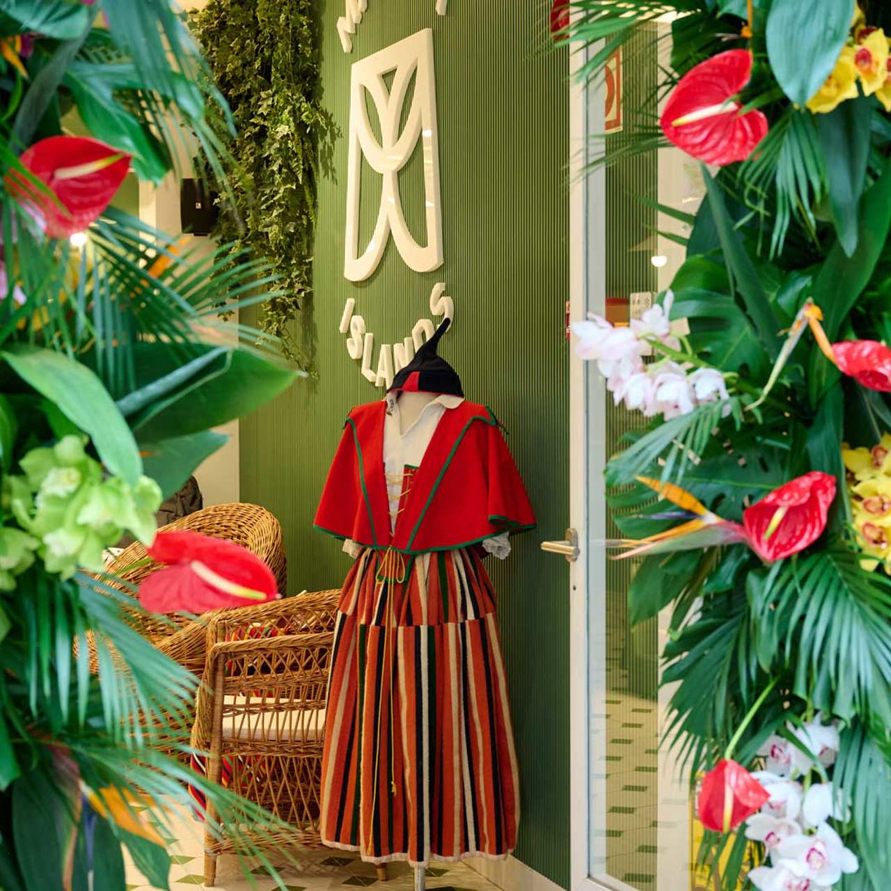 Entrance of the Madeira Tourism Office in Lisbon with a flower arch and a displayed villain costume.