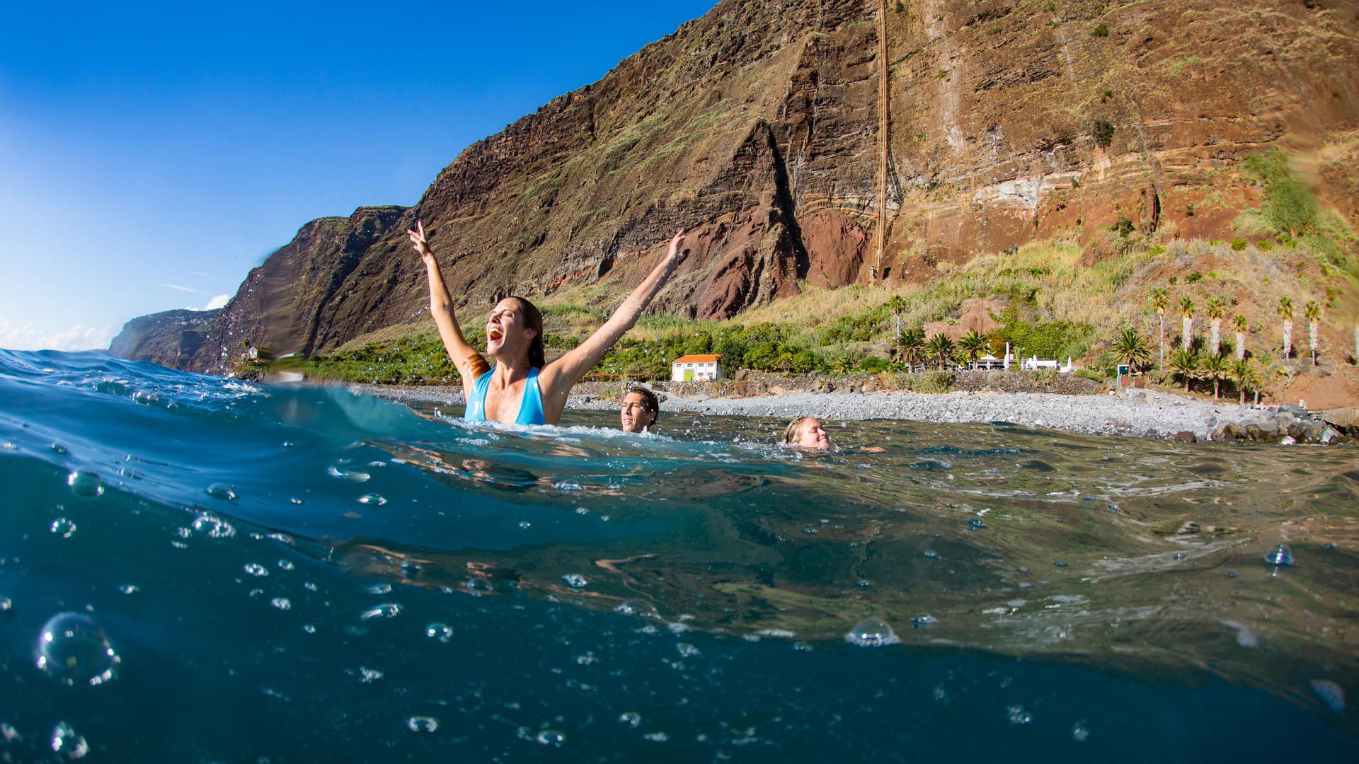 Three people at Fajã dos Padres by the sea and hillside.