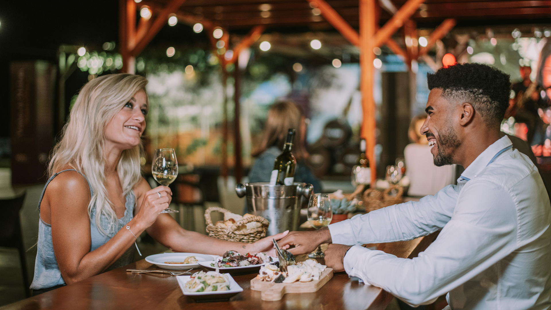 Casal a conversar enquanto desfruta de uma refeição acompanhada por vinho na Ilha da Madeira.