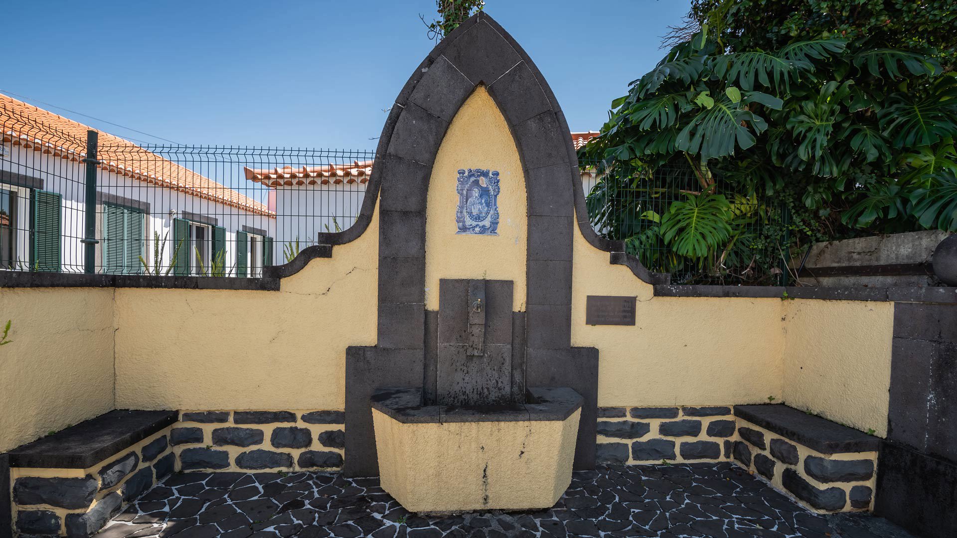 Gelber Brunnen neben Häusern mit grünen Pflanzen auf Madeira.