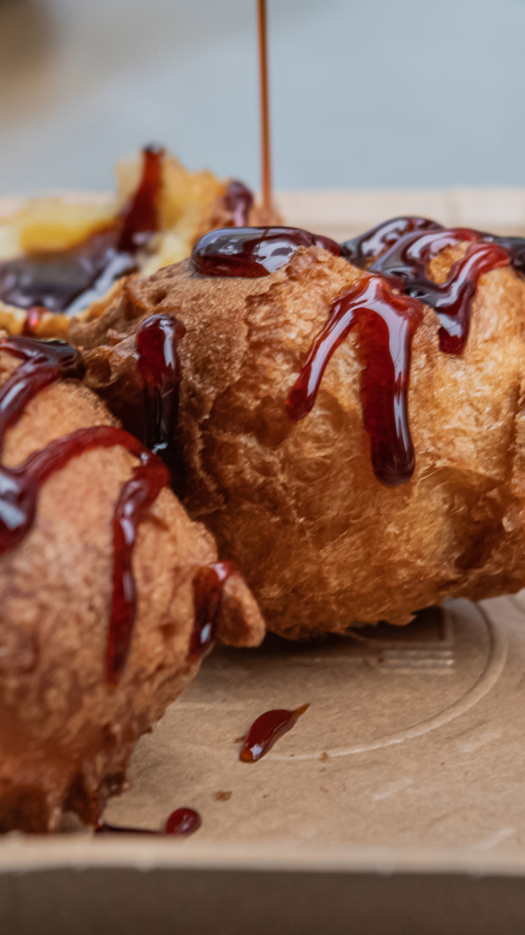 Malassadas auf einem Teller serviert, mit Zuckerrohrhonig darüber.