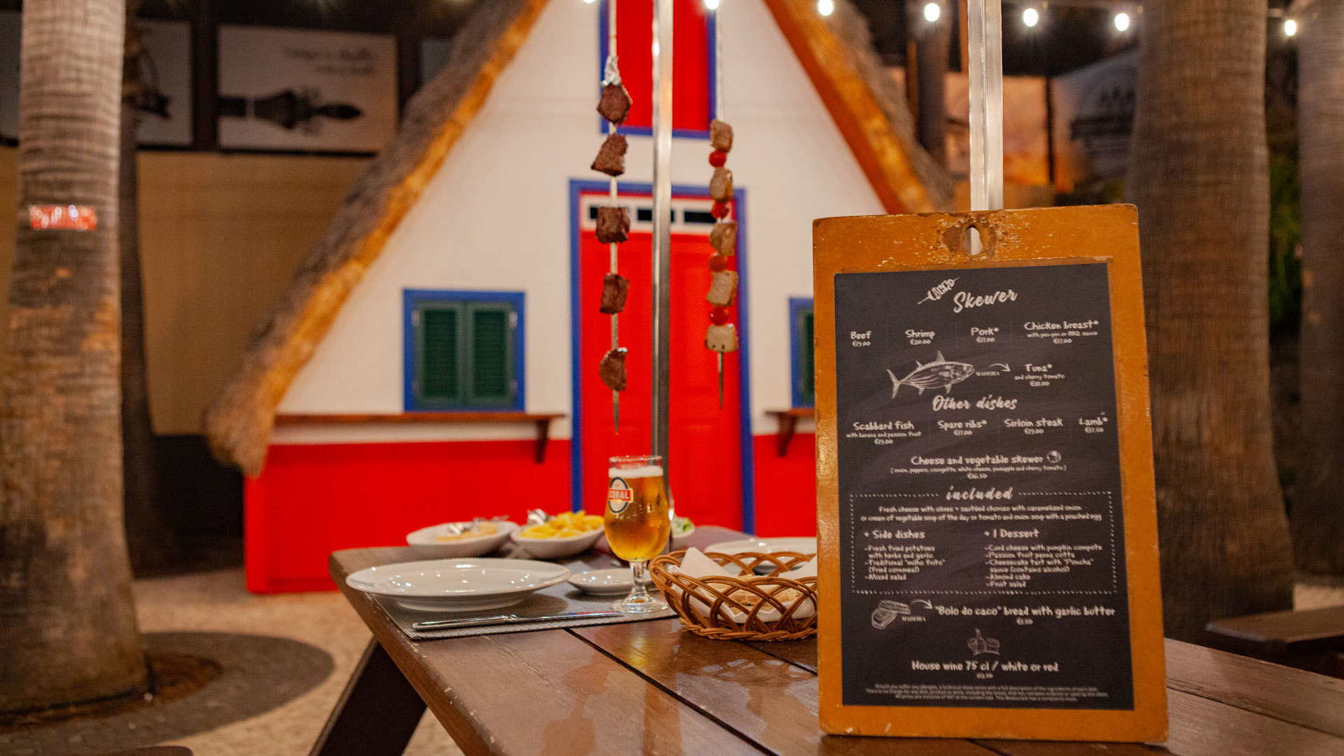 Table with food, drinks, and menu next to red and white triangular house.