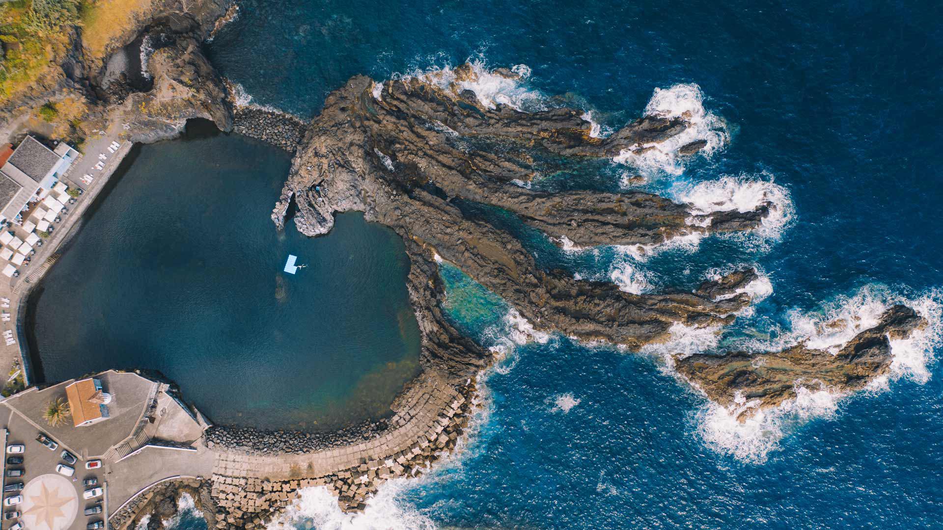 Drone aerial photo of a natural pool with waves on Madeira’s coast.