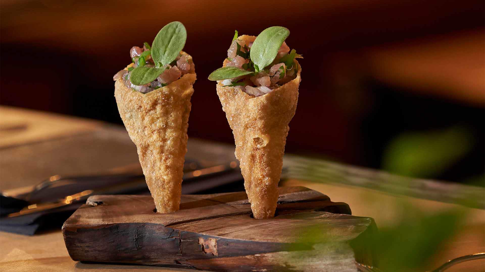 Cones filled with diced tuna topped with a plant.