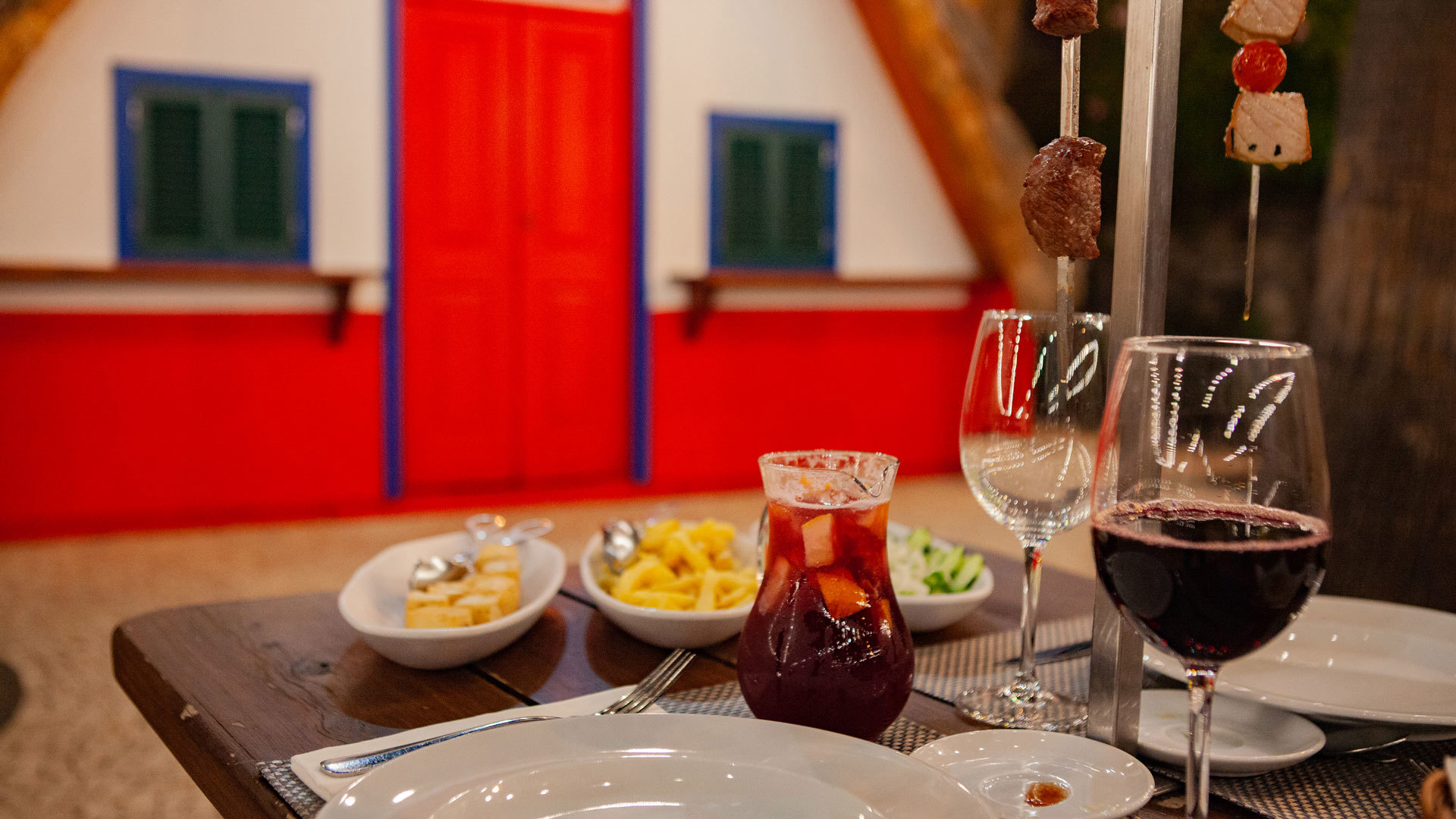 Table with food and a pitcher of sangria, served glasses, and fries.