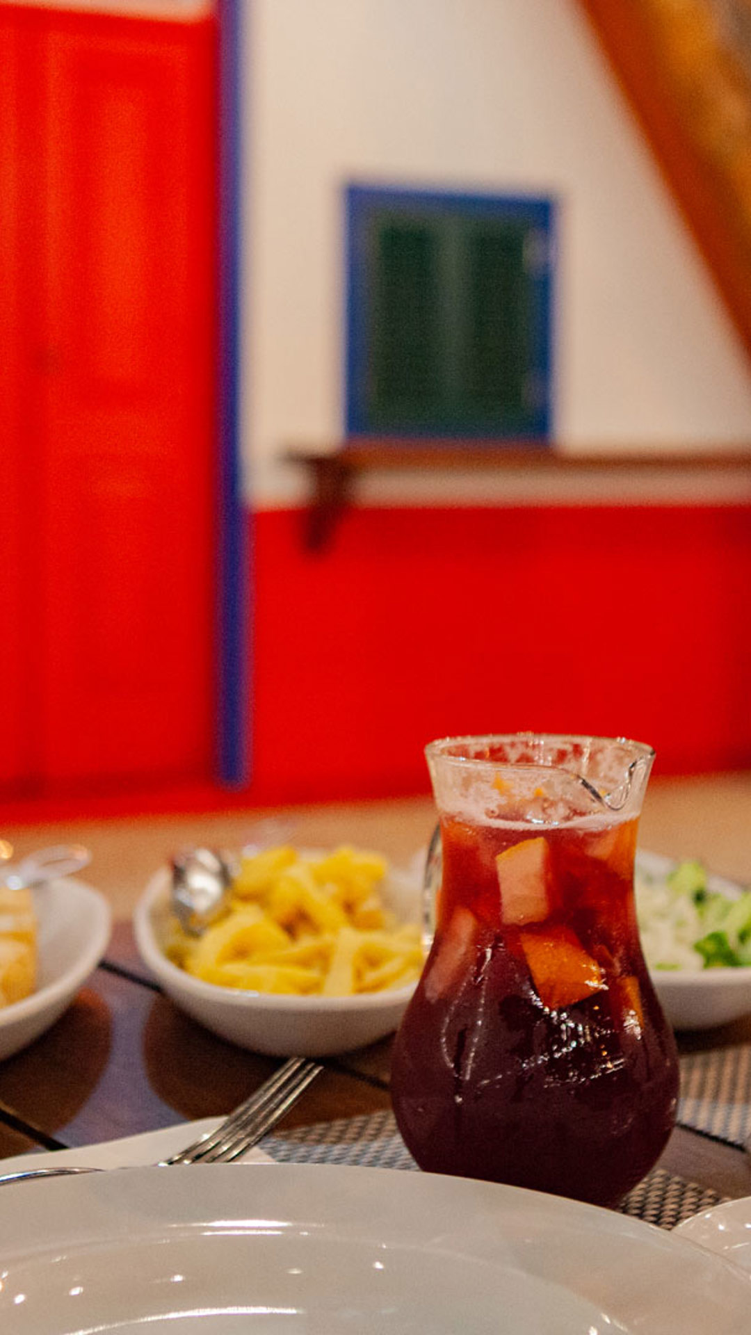 Tisch mit Essen und Krug Sangria, servierte Gläser und Pommes.