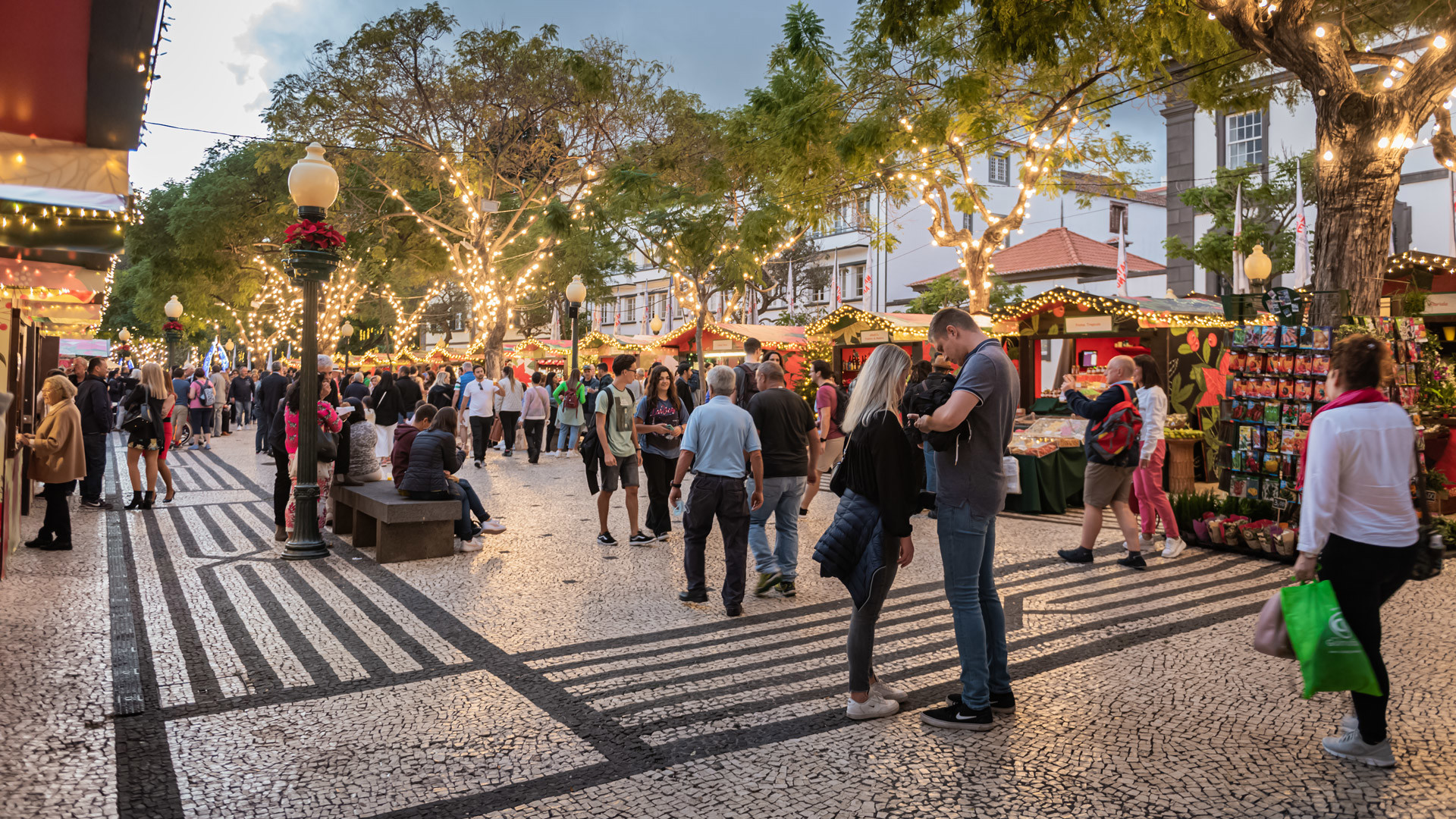 Personas junto a los puestos de Navidad con luces en la plaza central de Funchal.