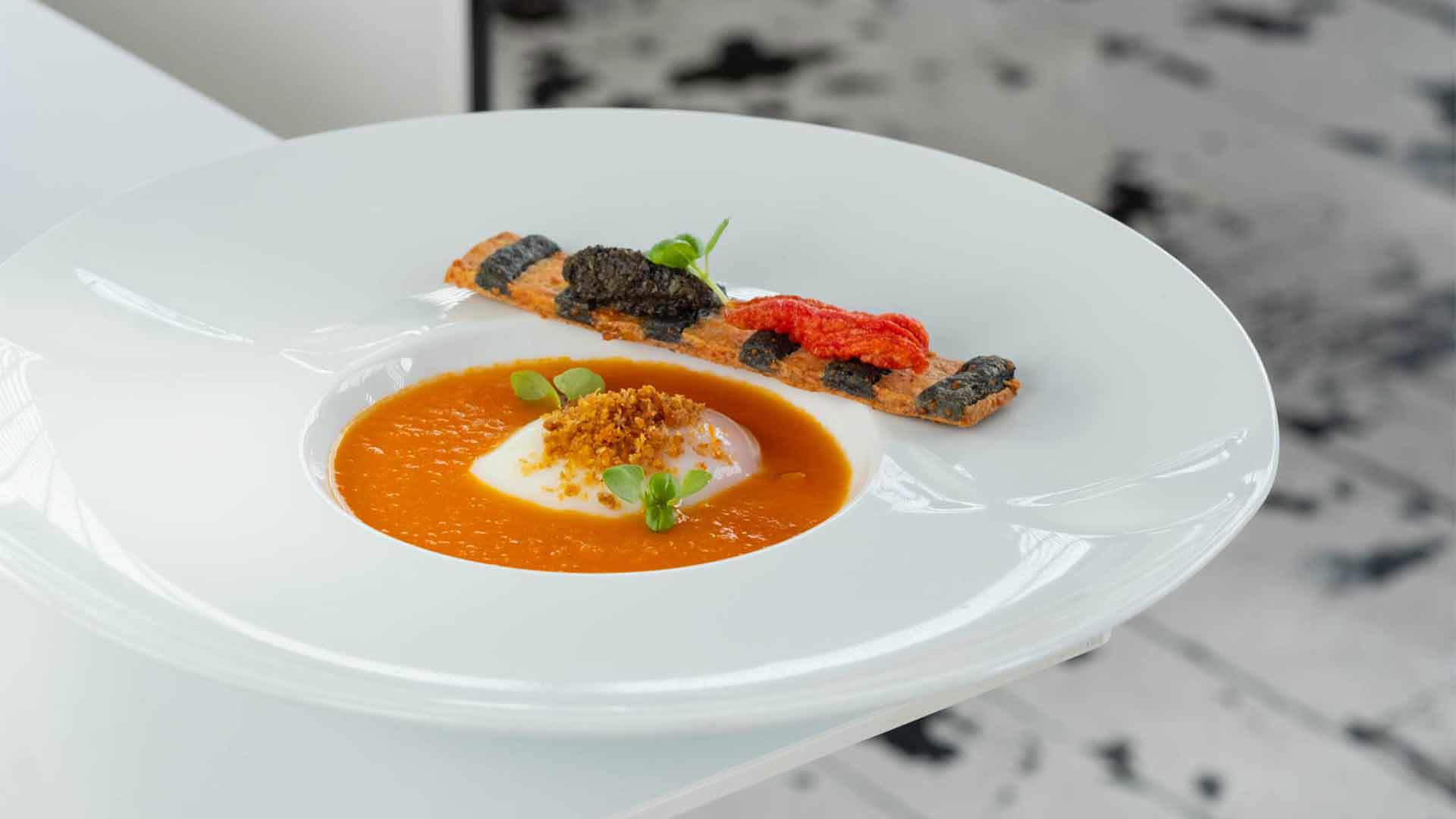 Plate with orange soup and decorative striped strip.