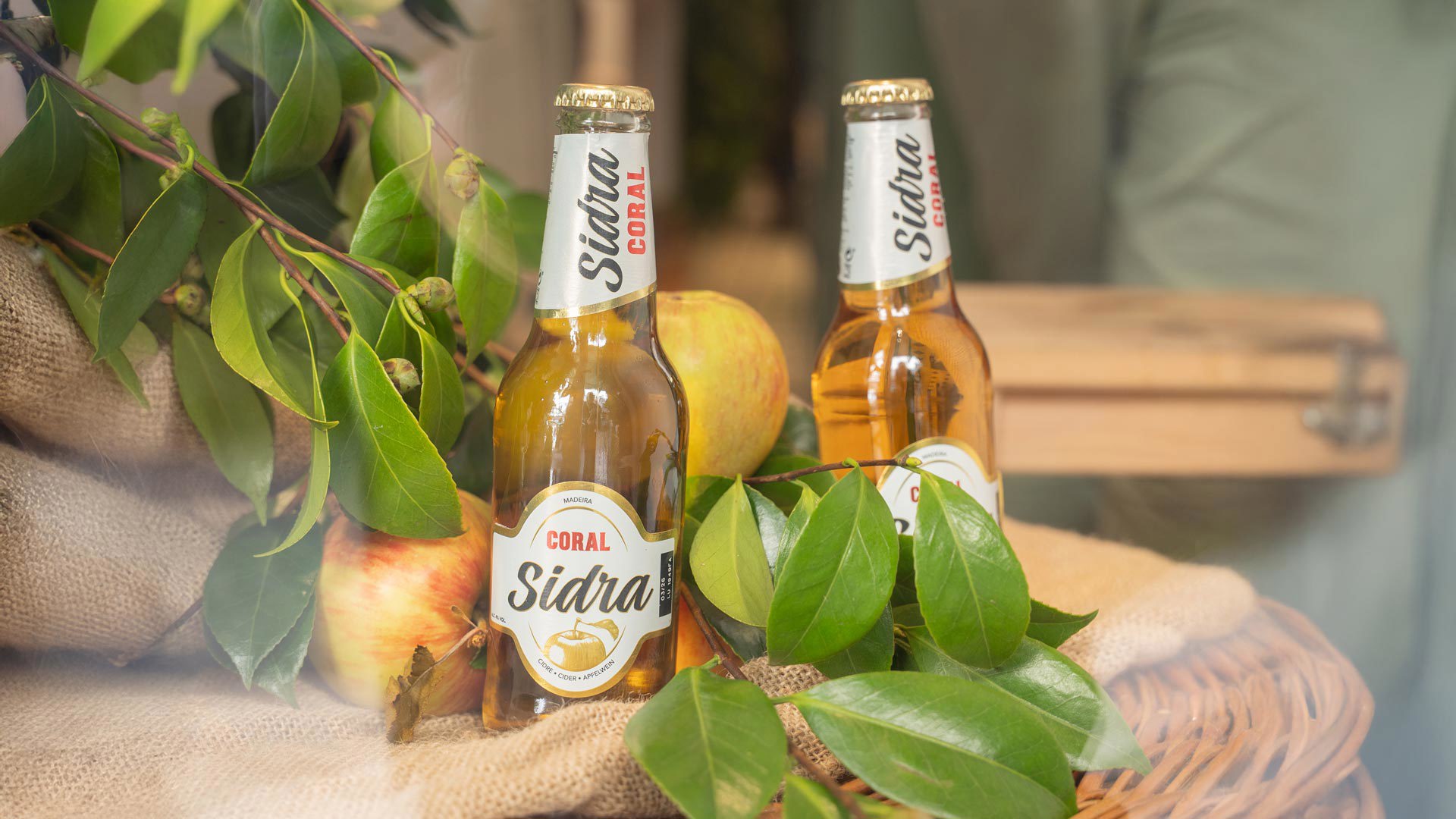 Coral cider bottles displayed with decorative leaves.