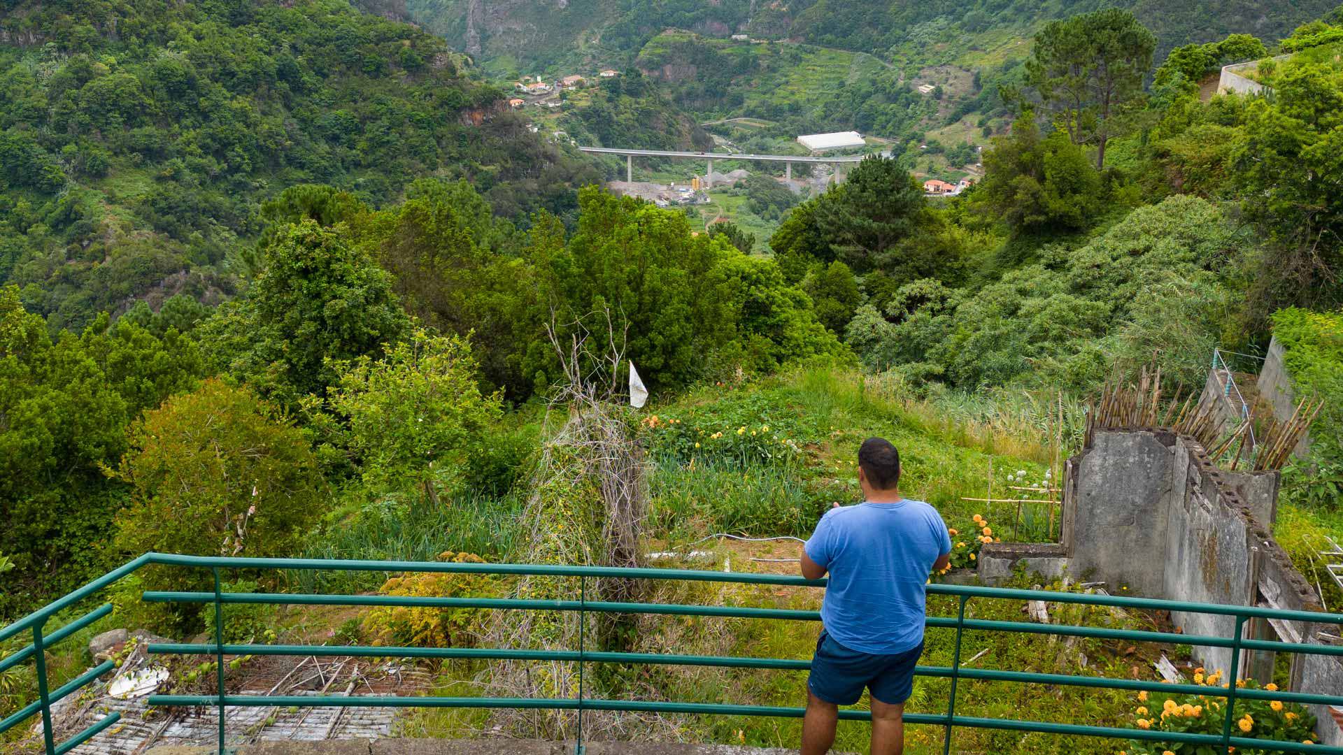 Man beside iron fence with green vegetation in Madeira.