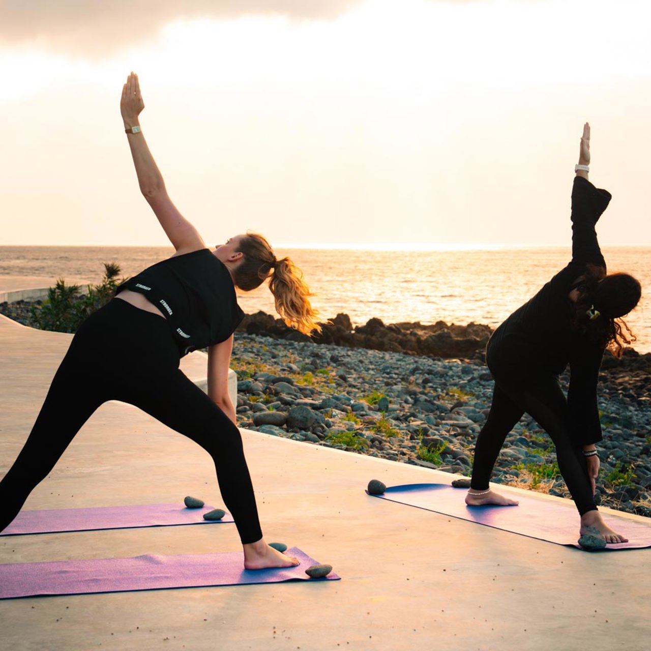 Zwei Frauen in Yogapose am Meer.