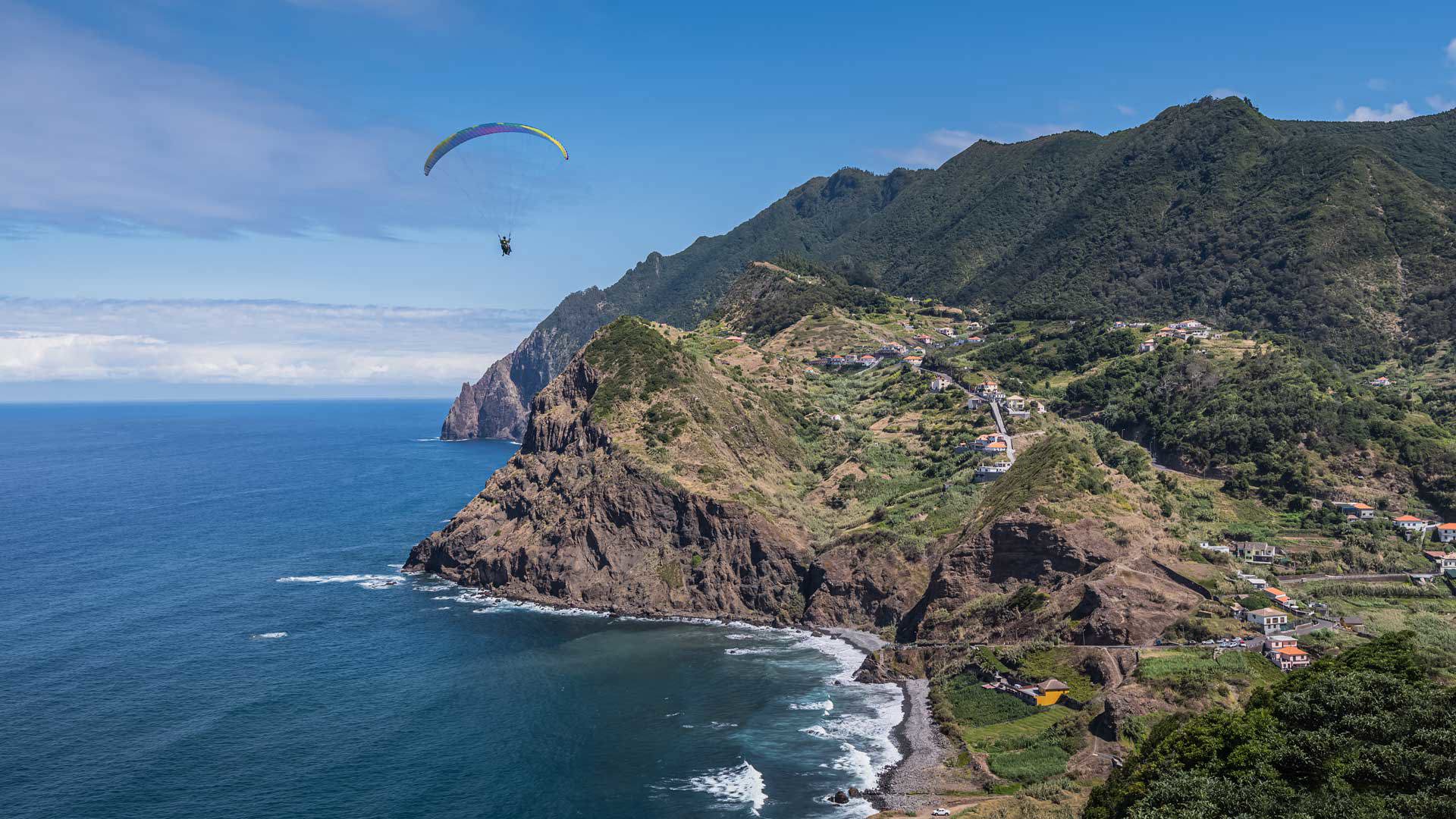 Paragliding over the sea with mountains in the background