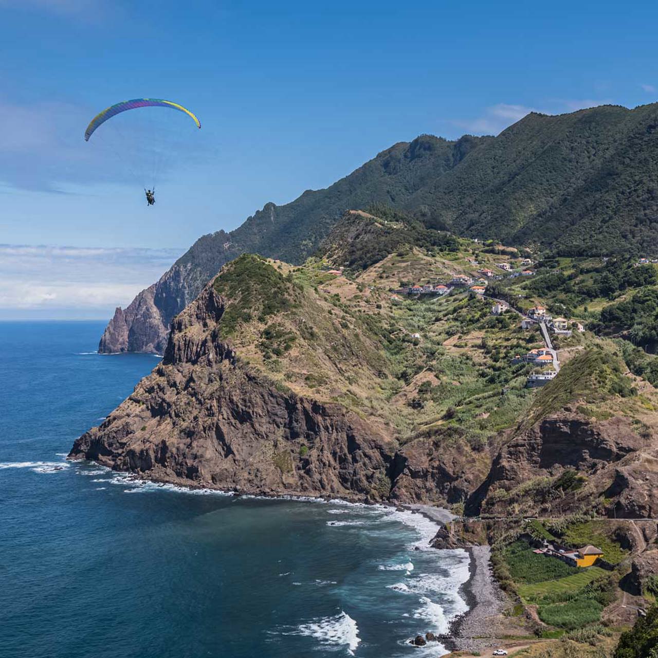Parapente sobre el mar con montañas al fondo