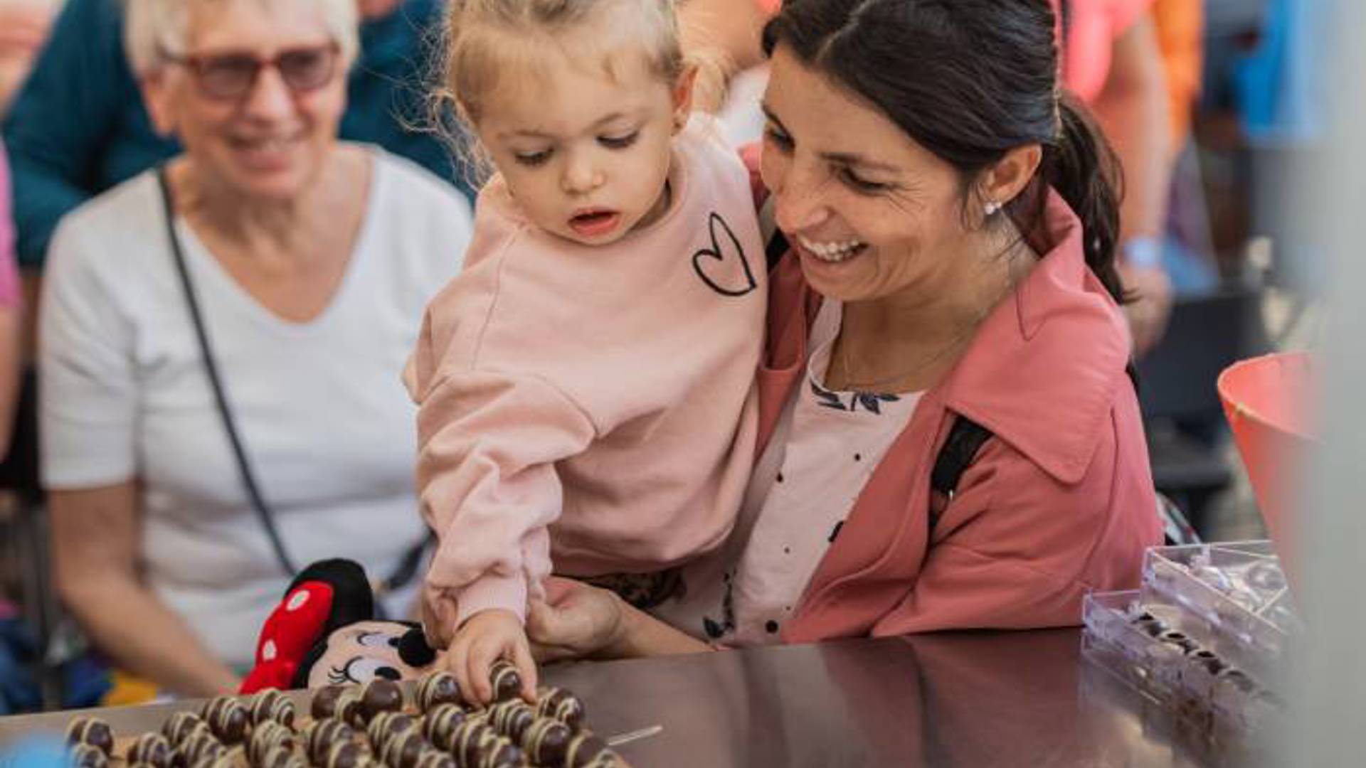 Mère et fille dégustant des chocolats sur un plateau lors des ateliers de Noël à Funchal.