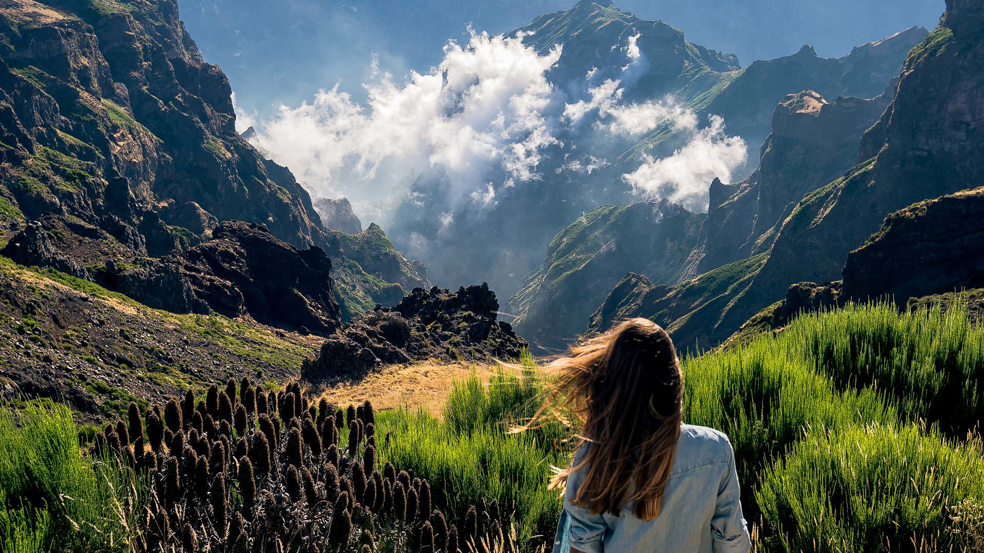 Woman among clouds in the mountains with green vegetation in Madeira.