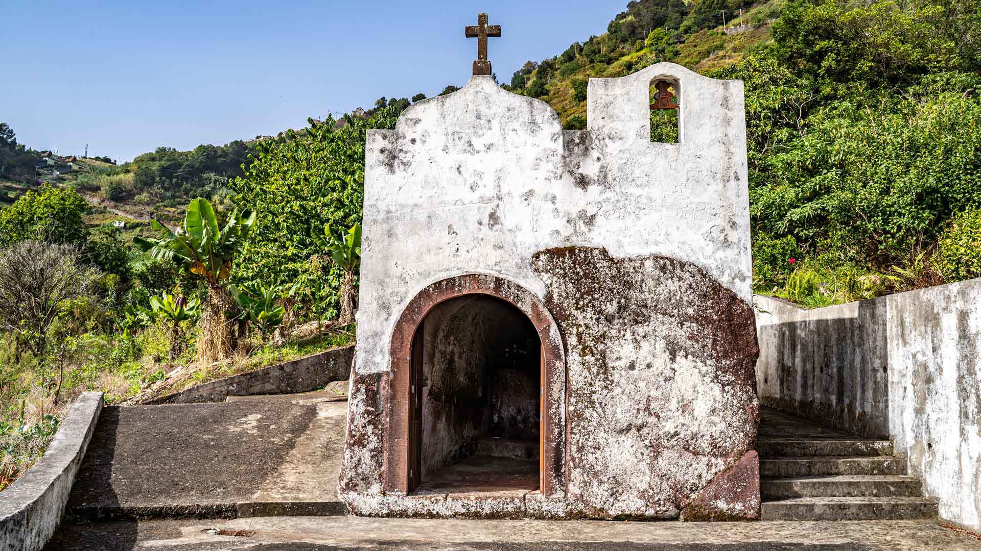 Capilla antigua con escaleras y plantas alrededor.