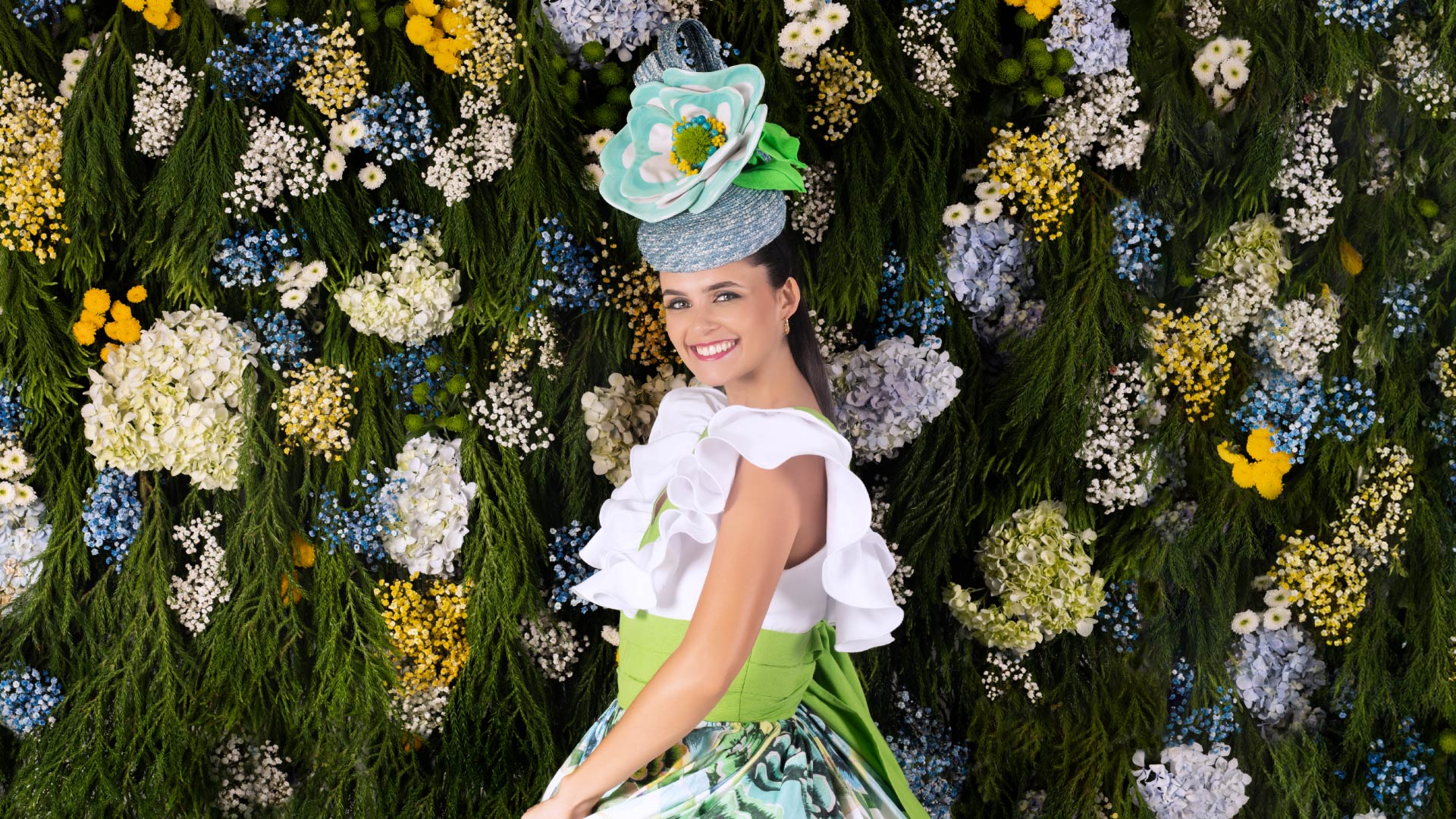 Woman with a flower in her hair beside a wall of flowers