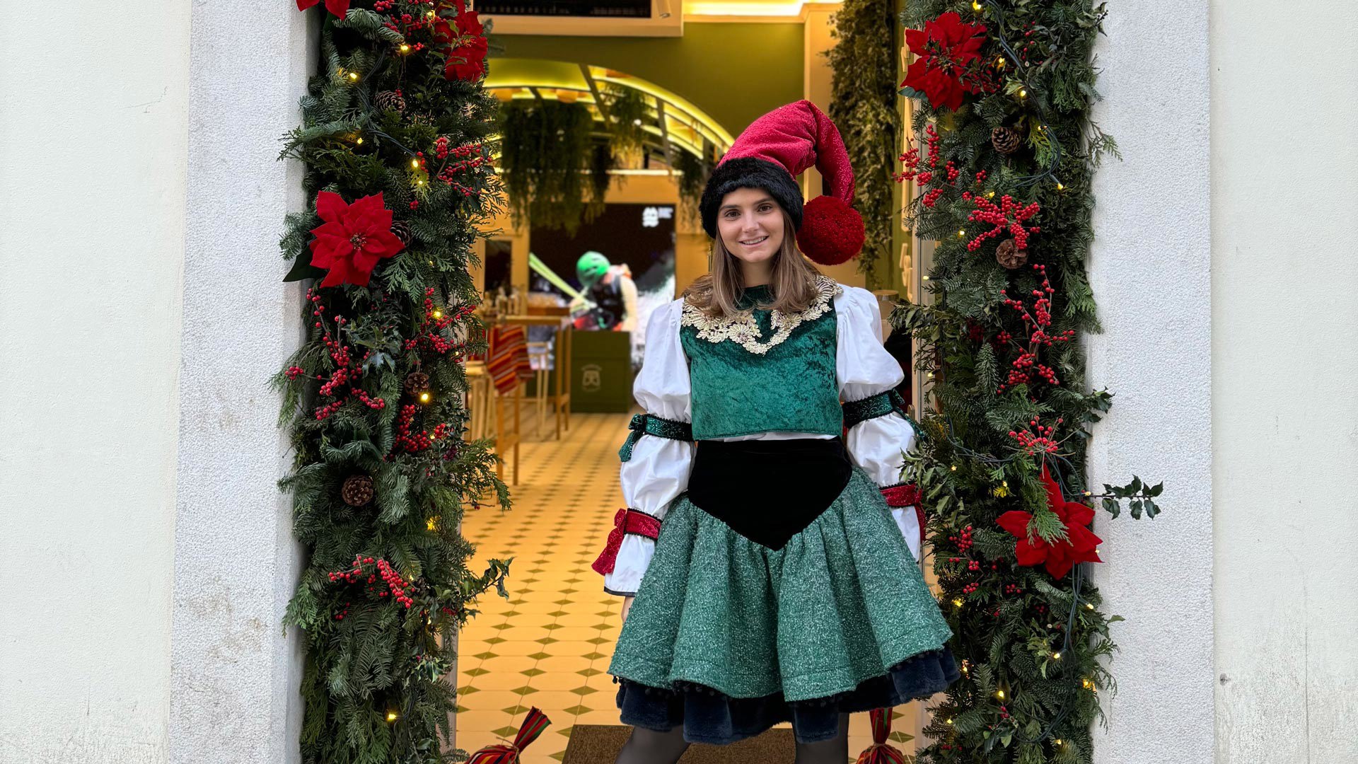 Entrance of the Madeira Tourism Office in Lisbon with a flower arch and a woman in a Christmas costume.