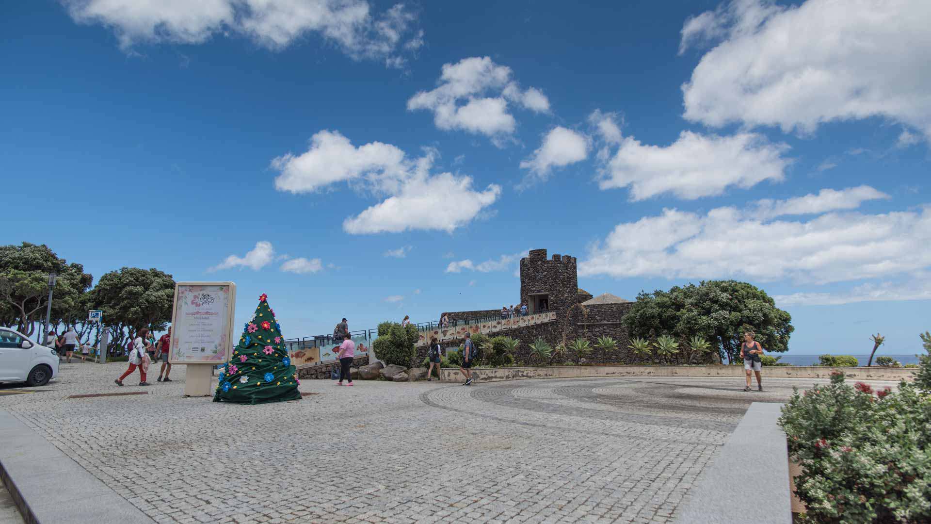Miradouro com pessoas a passear em jardim florido.