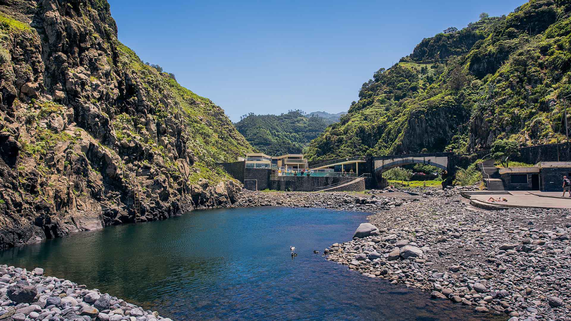 Lago numa praia de calhau junto à montanha na Madeira.