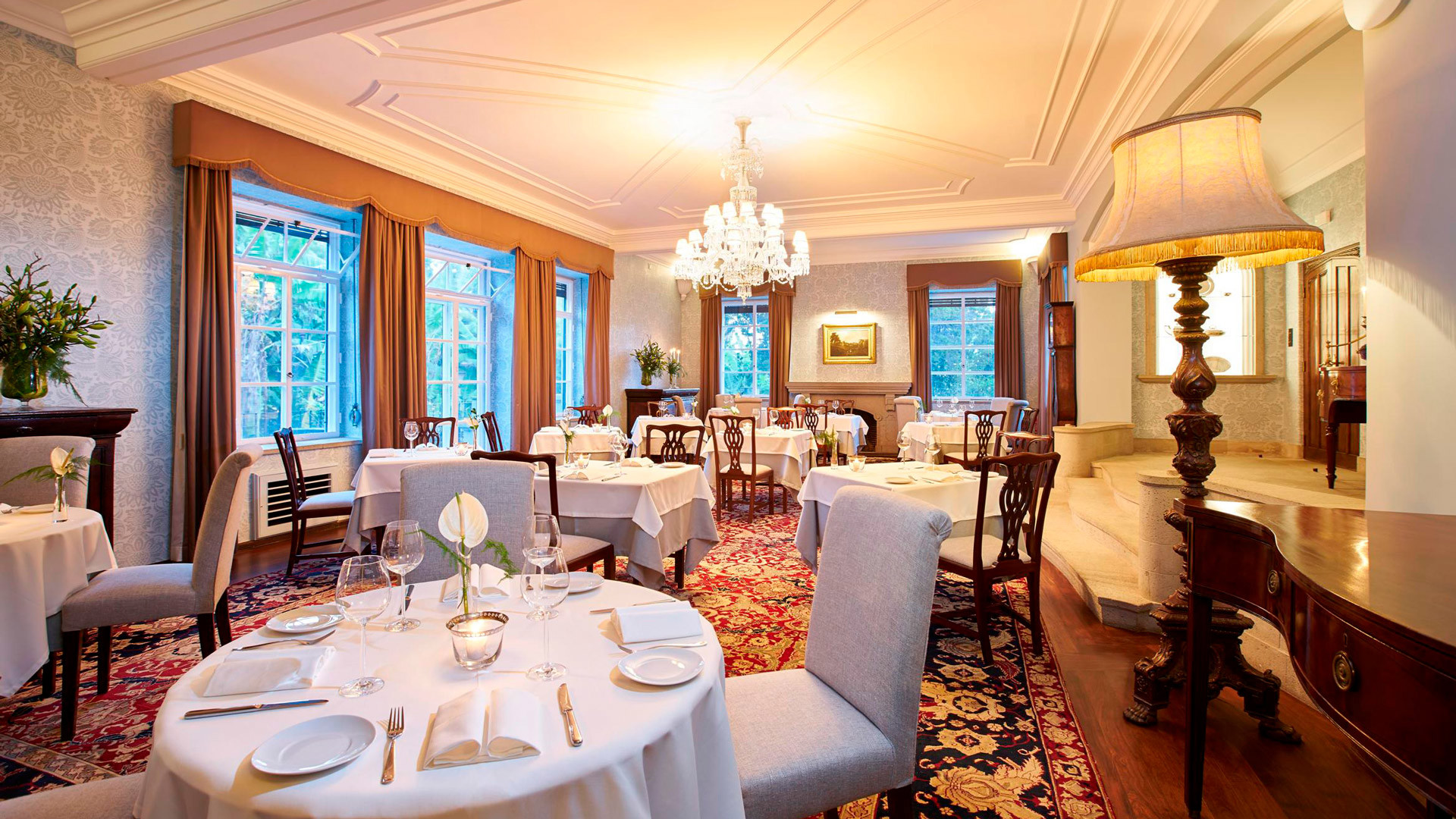 Room decorated with set tables, chairs, and central lamp.