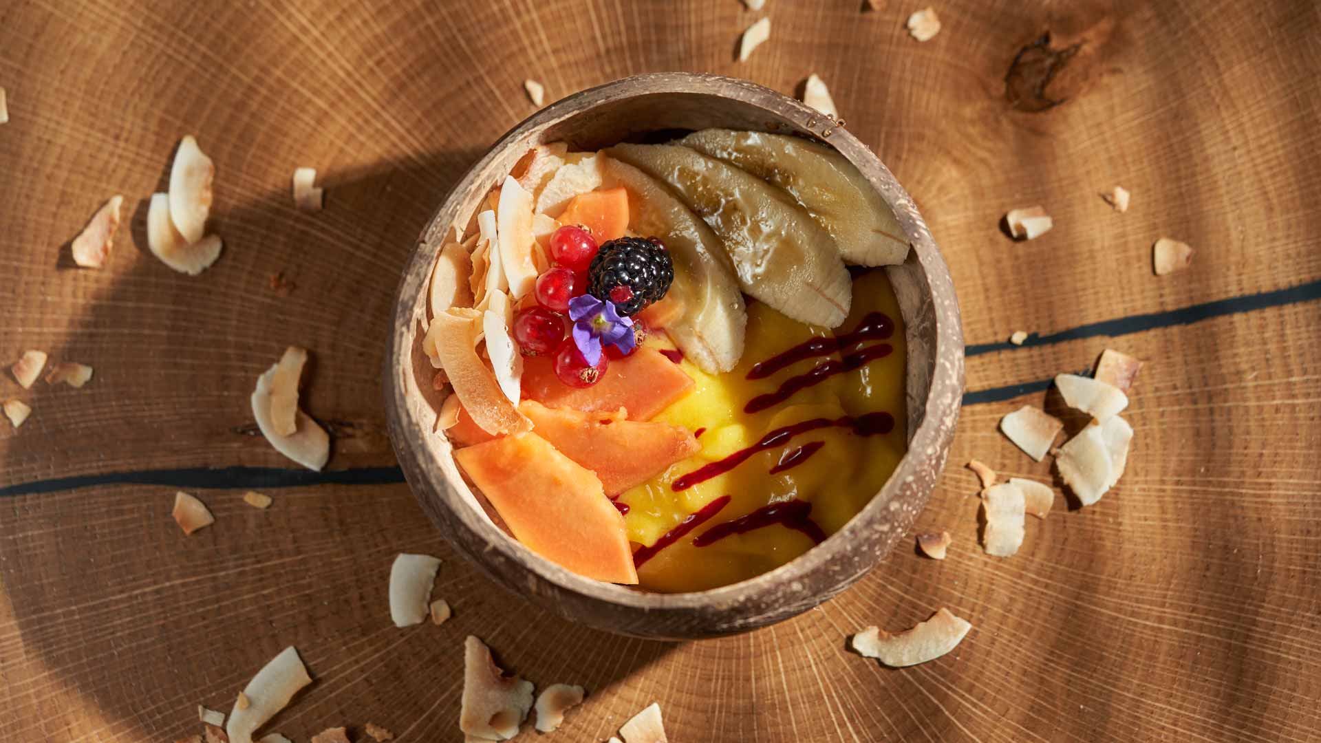 Bowl com frutas e coco sobre a mesa.