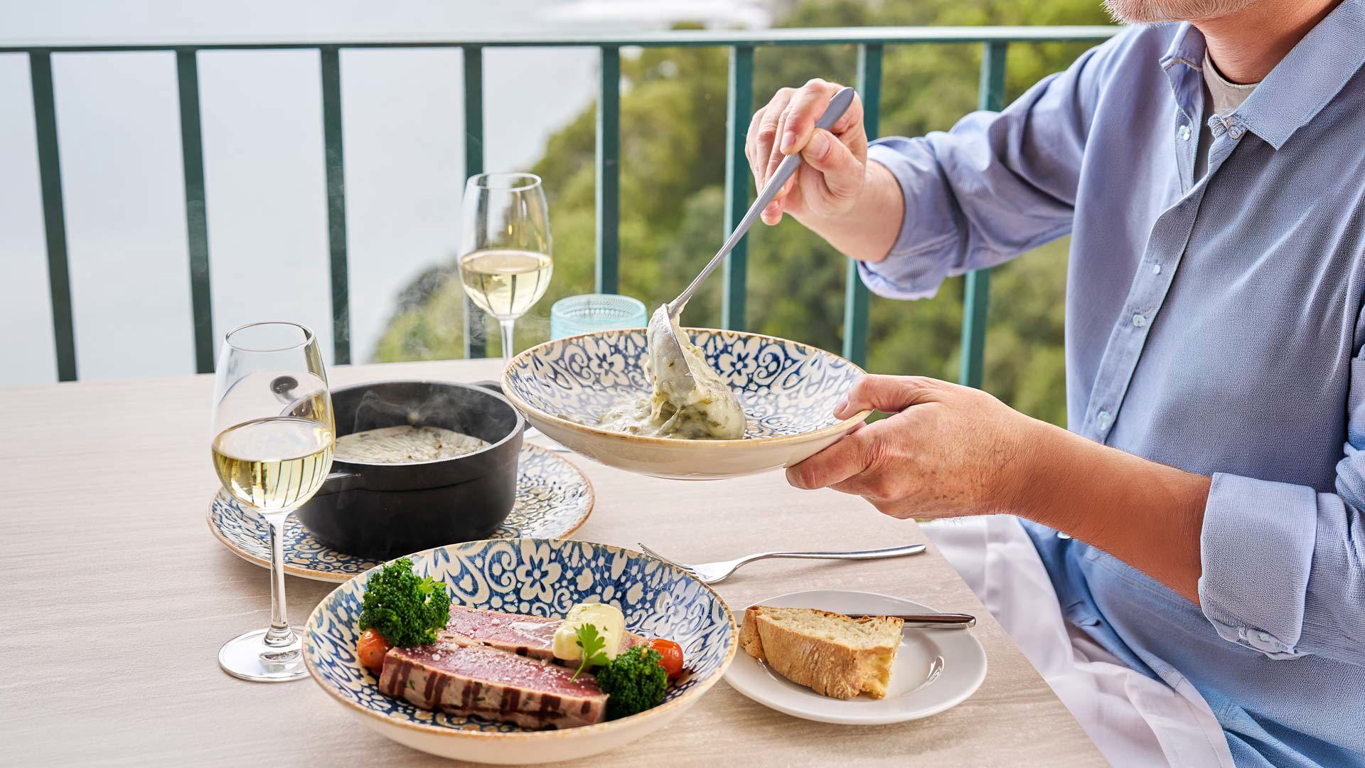 Repas composé d’un steak de thon, de maïs bouilli et de vin blanc servi à table.