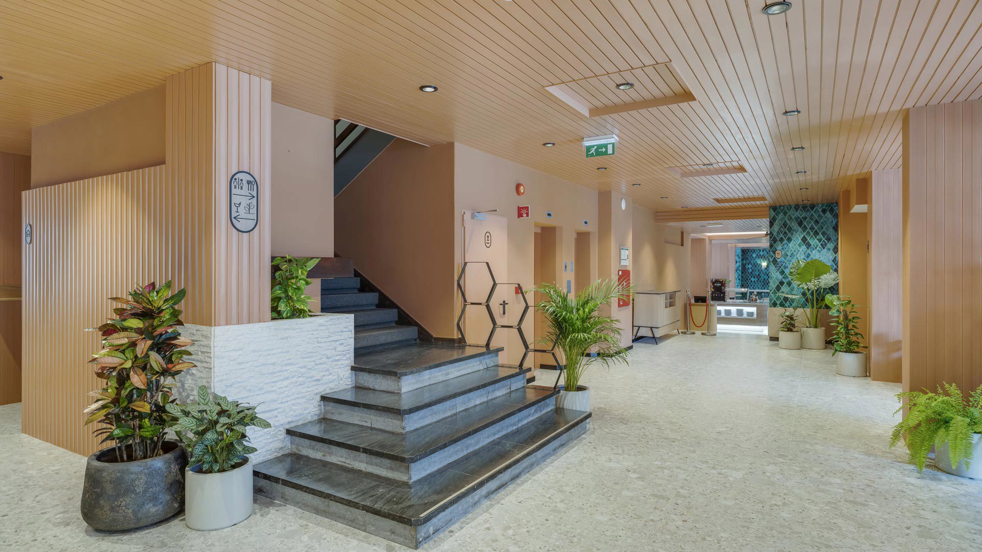 Hall de entrada do Editory Garden Carmo Funchal, com escadaria moderna e vasos com plantas.