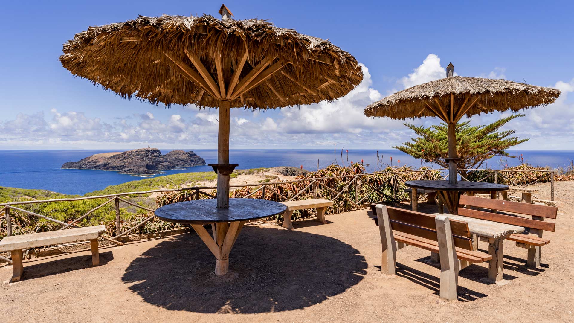 Campsite area with umbrellas and tables by the sea.